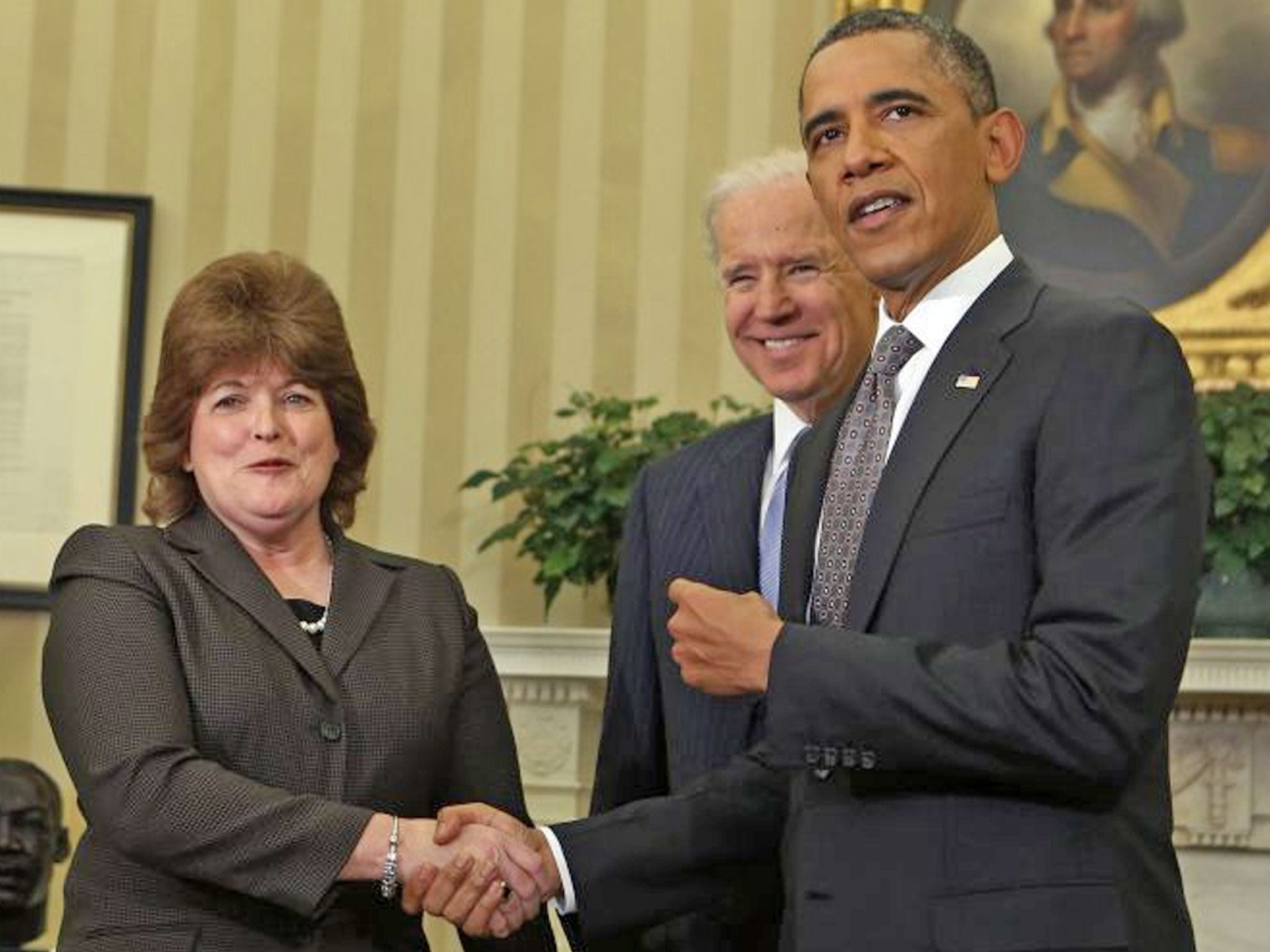 Barack Obama shakes hands with US Secret Service agent Julia Pierson after she is sworn in as the first woman Director of the Secret Service