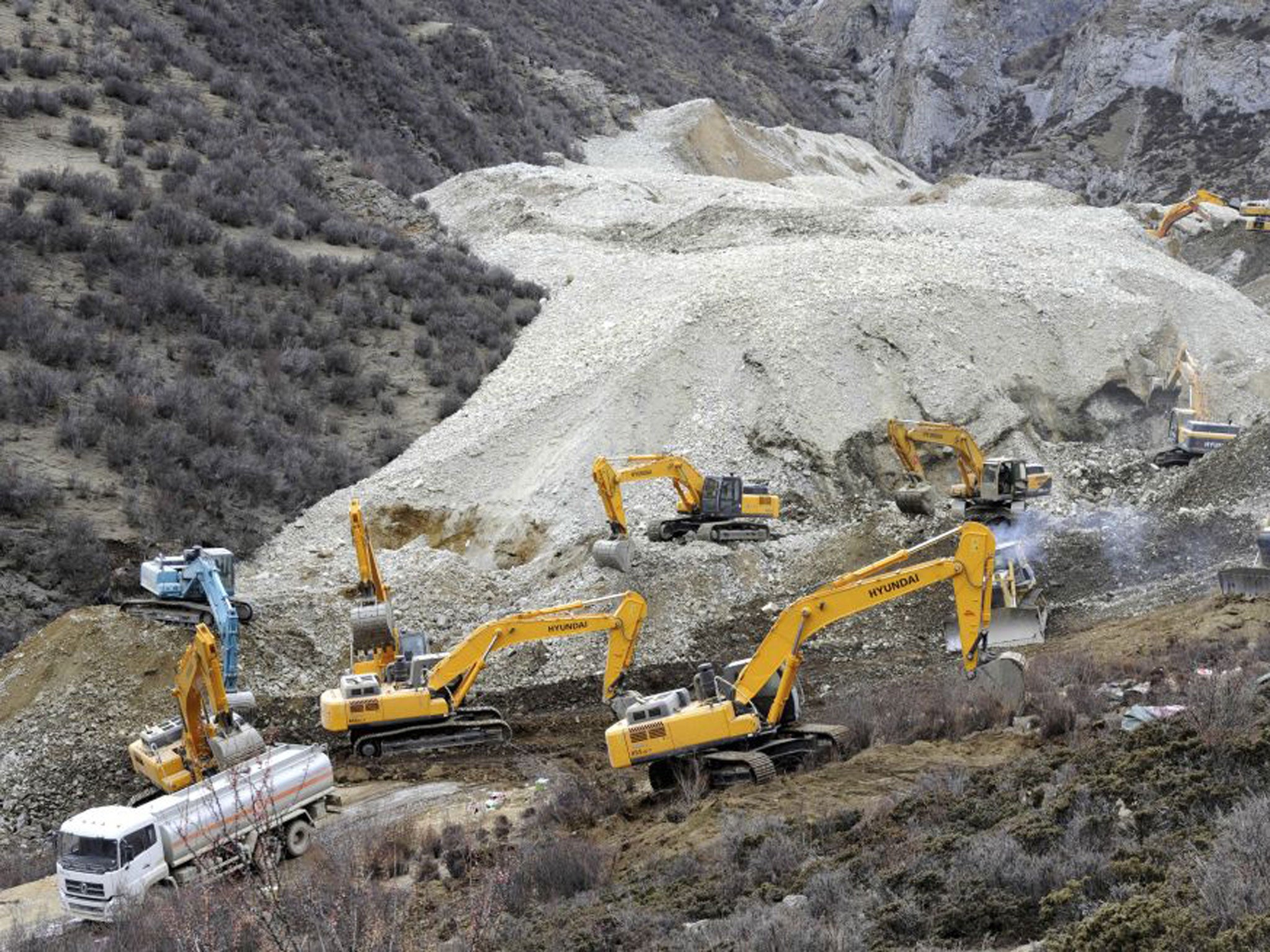 Earthmovers remove rocks and mud on the scene where the landslide hit