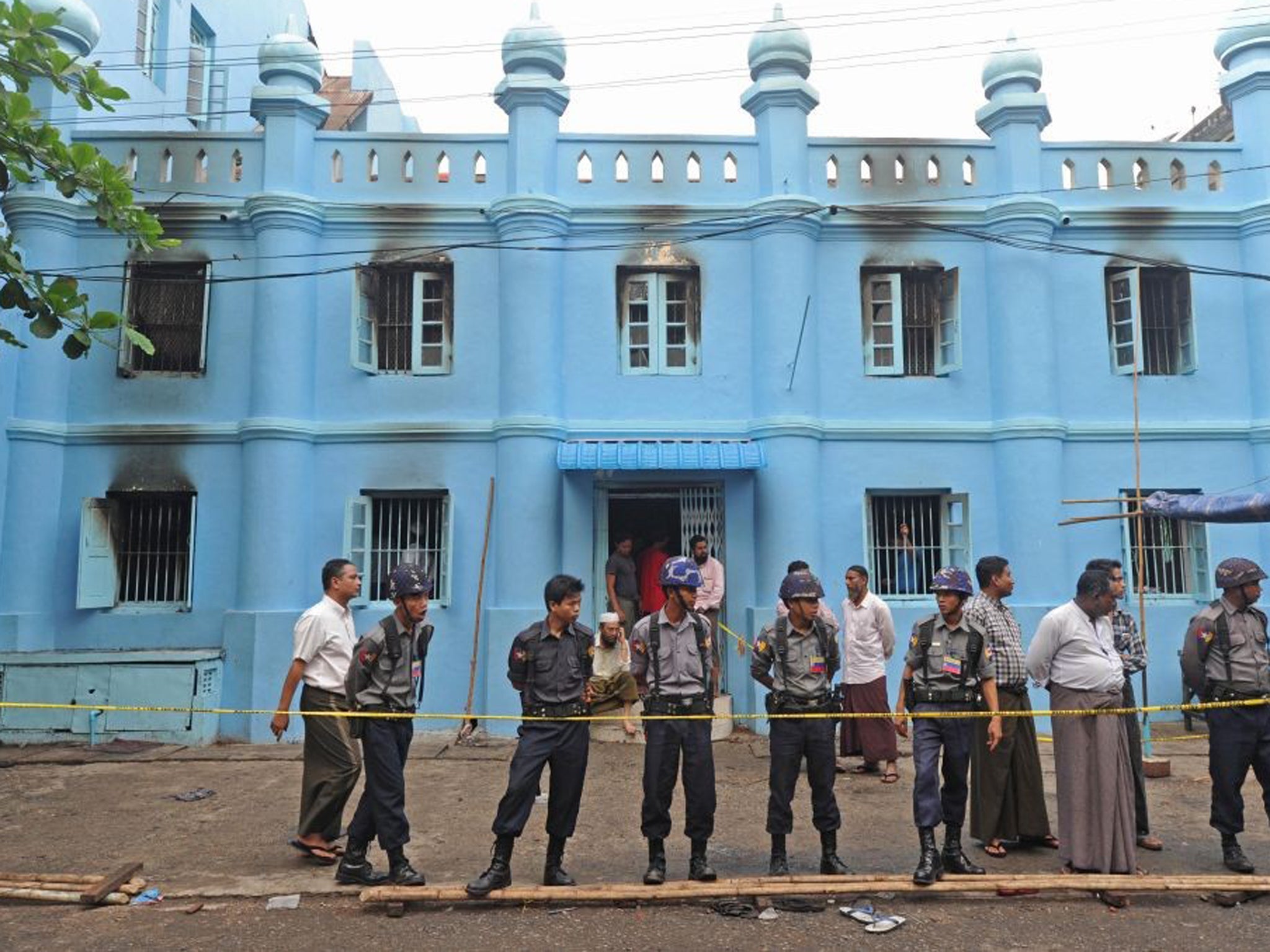 Police officers stand guard outside the mosque in Yangon following the fire