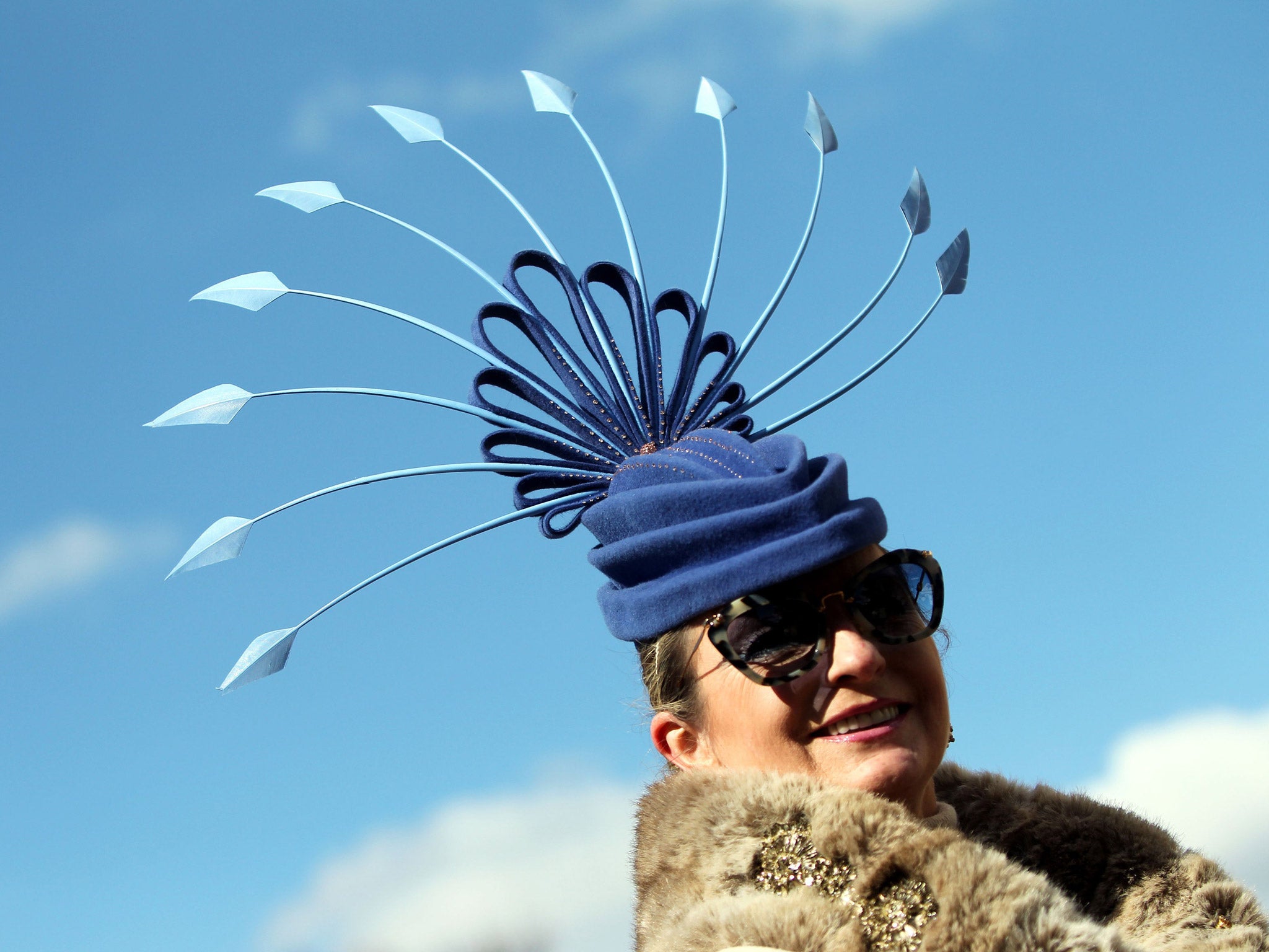 One lady wears a striking hat styled like a peacock's tail feathers