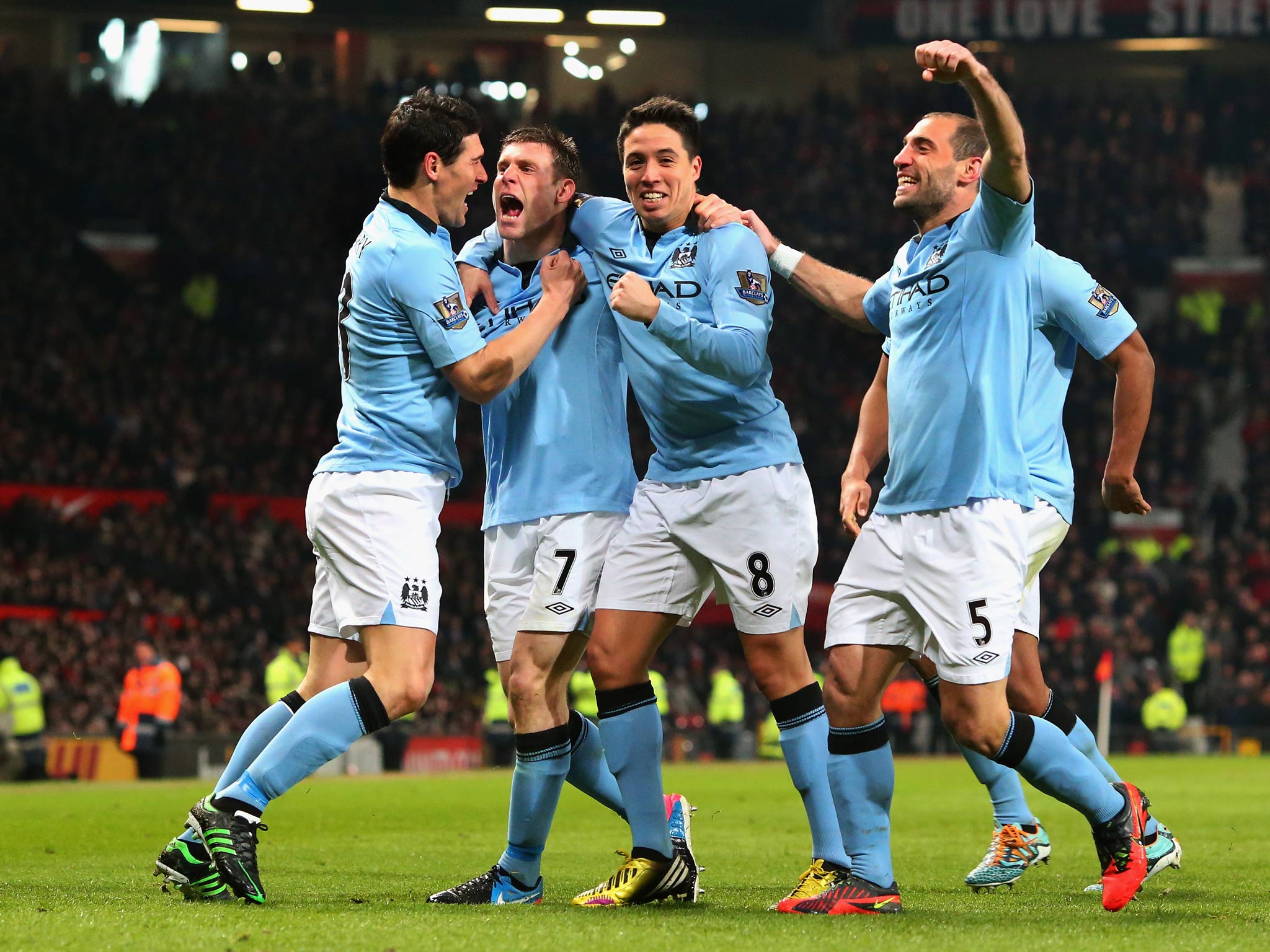 James Milner celebrates with his City team-mates after scoring against United