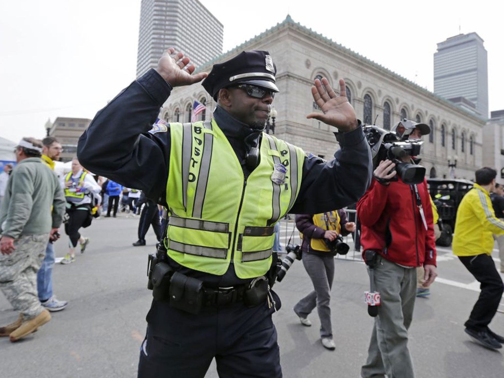 A Boston police officer clears Boylston Street following an explosion at the finish line of the 2013 Boston Marathon