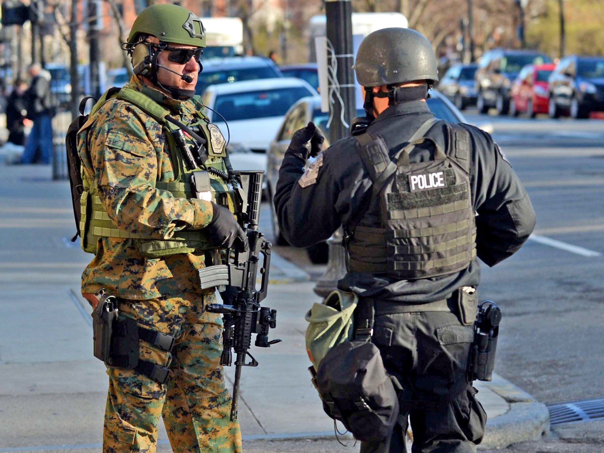 A heavily armed Boston police officer and a S.W.A.T. team police officer stand guard in front of the Taj Hotel, Boston