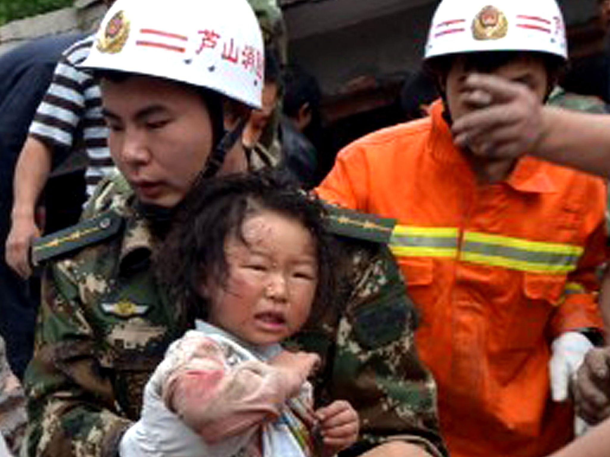 Disaster zone: A rescuer carries a child to safety after she was pulled out of her collapsed home after an earthquake hit Ya'an City