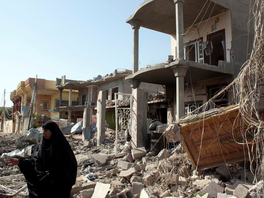 A woman gestures as she stands in the debris following three near-simultaneous car bombs in Tuz Khurmatu, which lies 175 kilometres (110 miles) north of Baghdad, on April 15, 2013. More than a dozen bombings across Iraq killed at least 19 people in the la