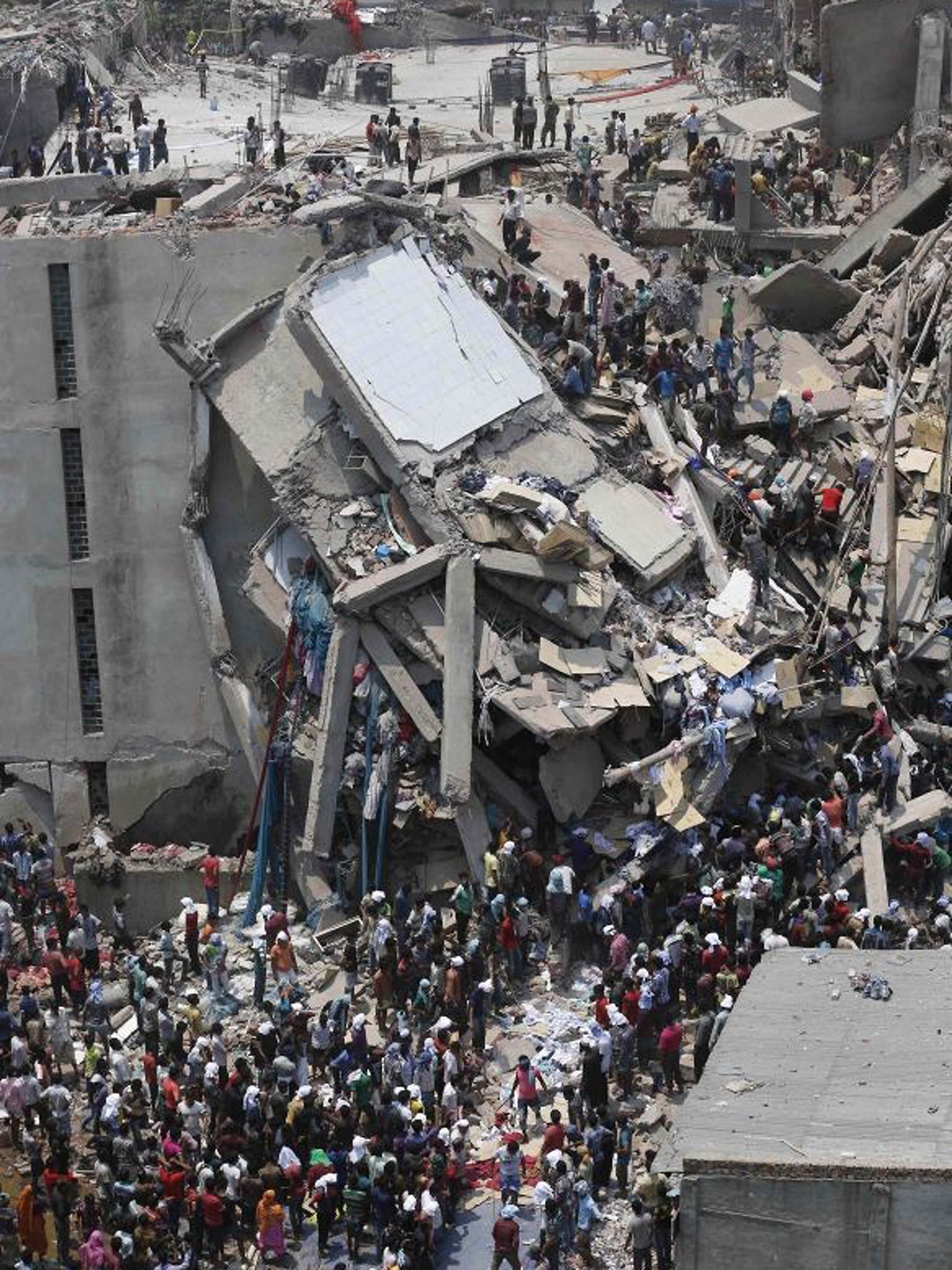 People rescue garment workers trapped under rubble at the Rana Plaza building after it collapsed, in Savar, 30 km (19 miles) outside Dhaka