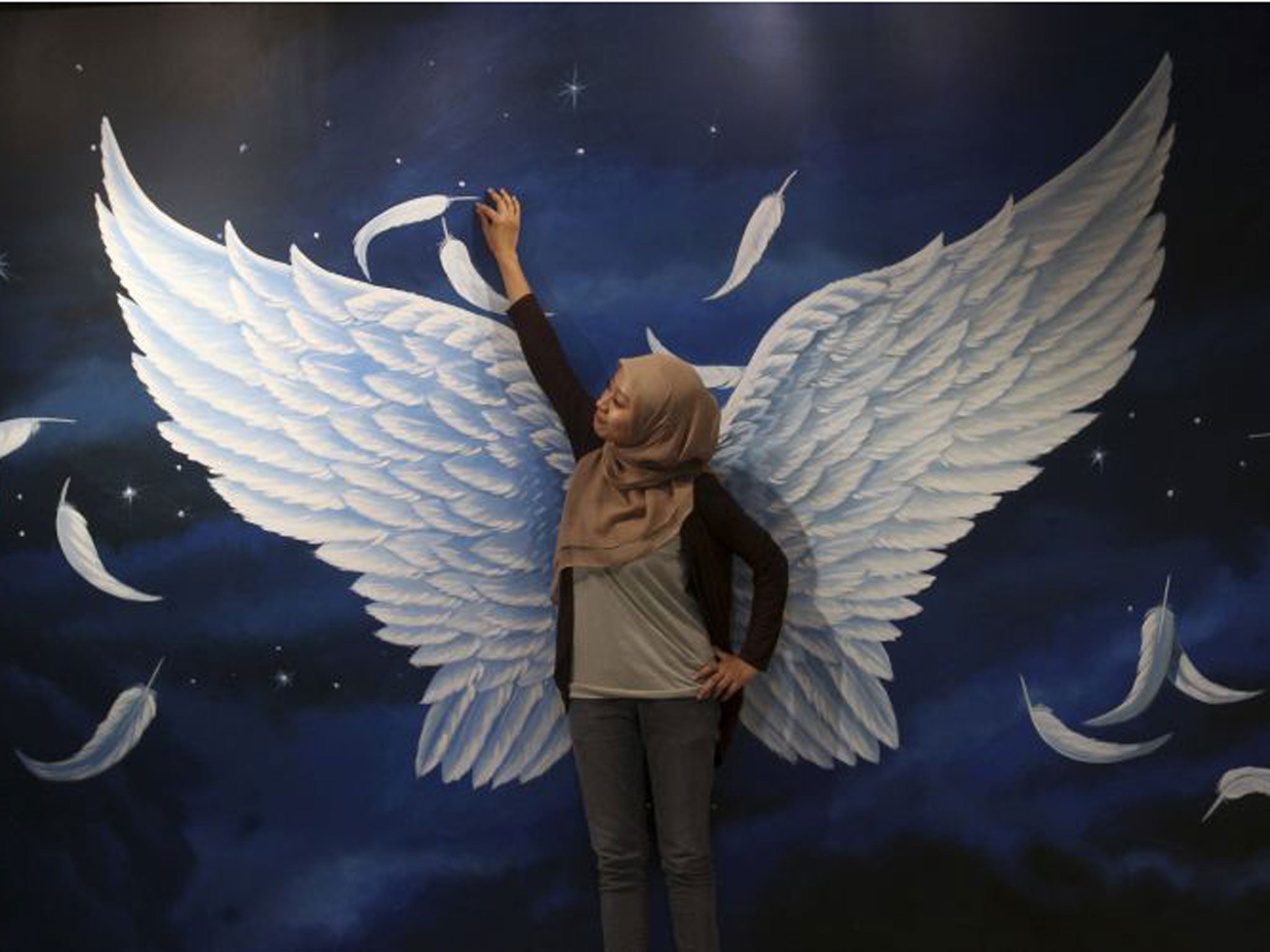 29 April 2013: An Indonesian Muslim woman poses with a 3D art during a Trick Art exhibition in Jakarta, Indonesia