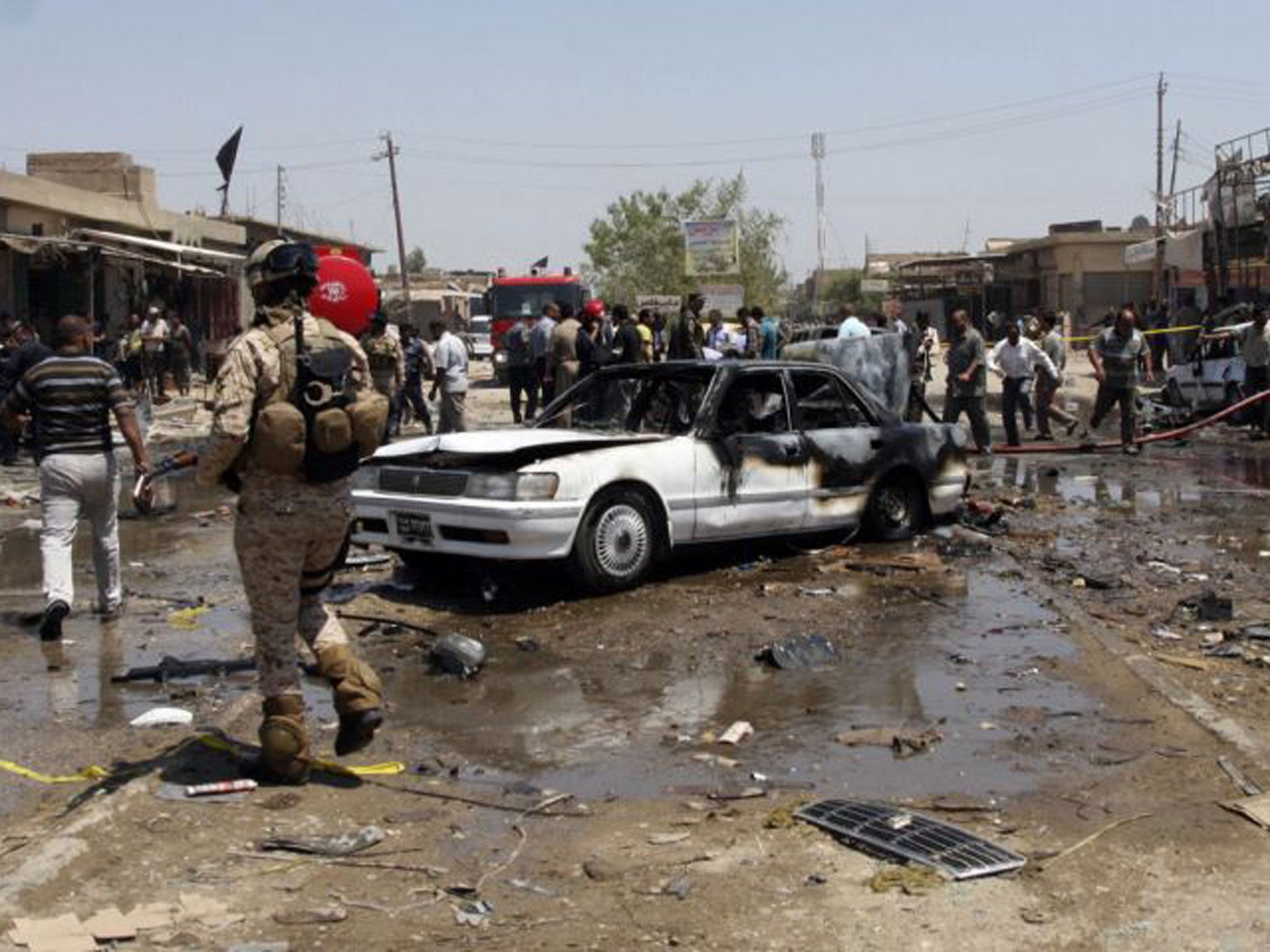 Civilians and security forces gather at the scene of a car bomb attack in the southern Shiite city of Karbala, 50 miles (80 kilometers) south of Baghdad, Iraq