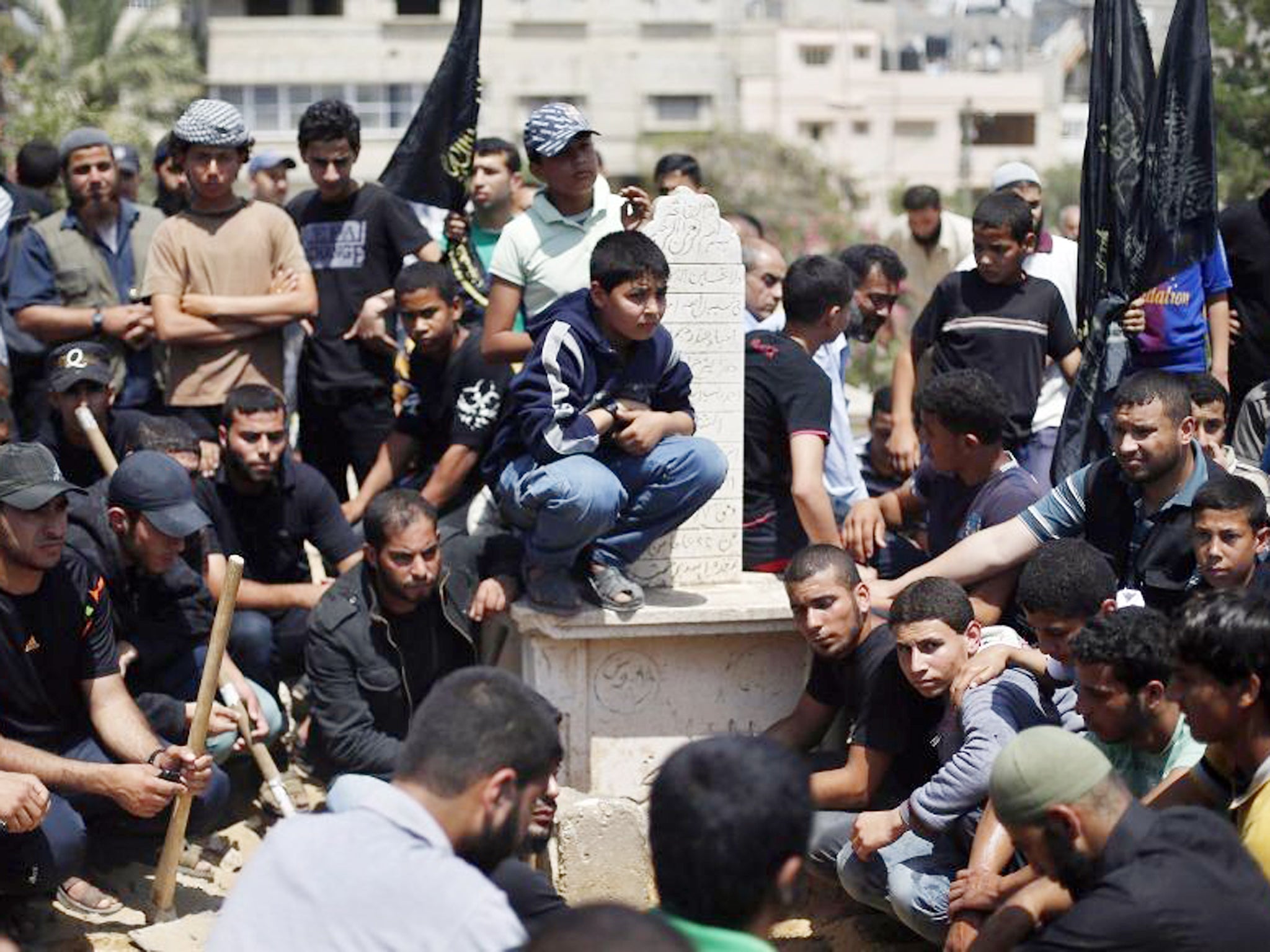 Palestinians sit around the grave of Haitham Mishal in Gaza City