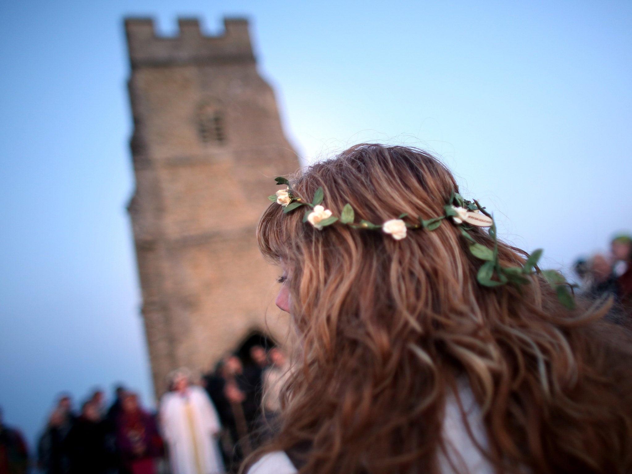 People gather in a circle to listen as Rollo Maughfling, (not pictured) the Archdruid of Glastonbury and Stonehenge conducts a Beltane dawn celebration service in front of St. Michael's Tower on Glastonbury Tor