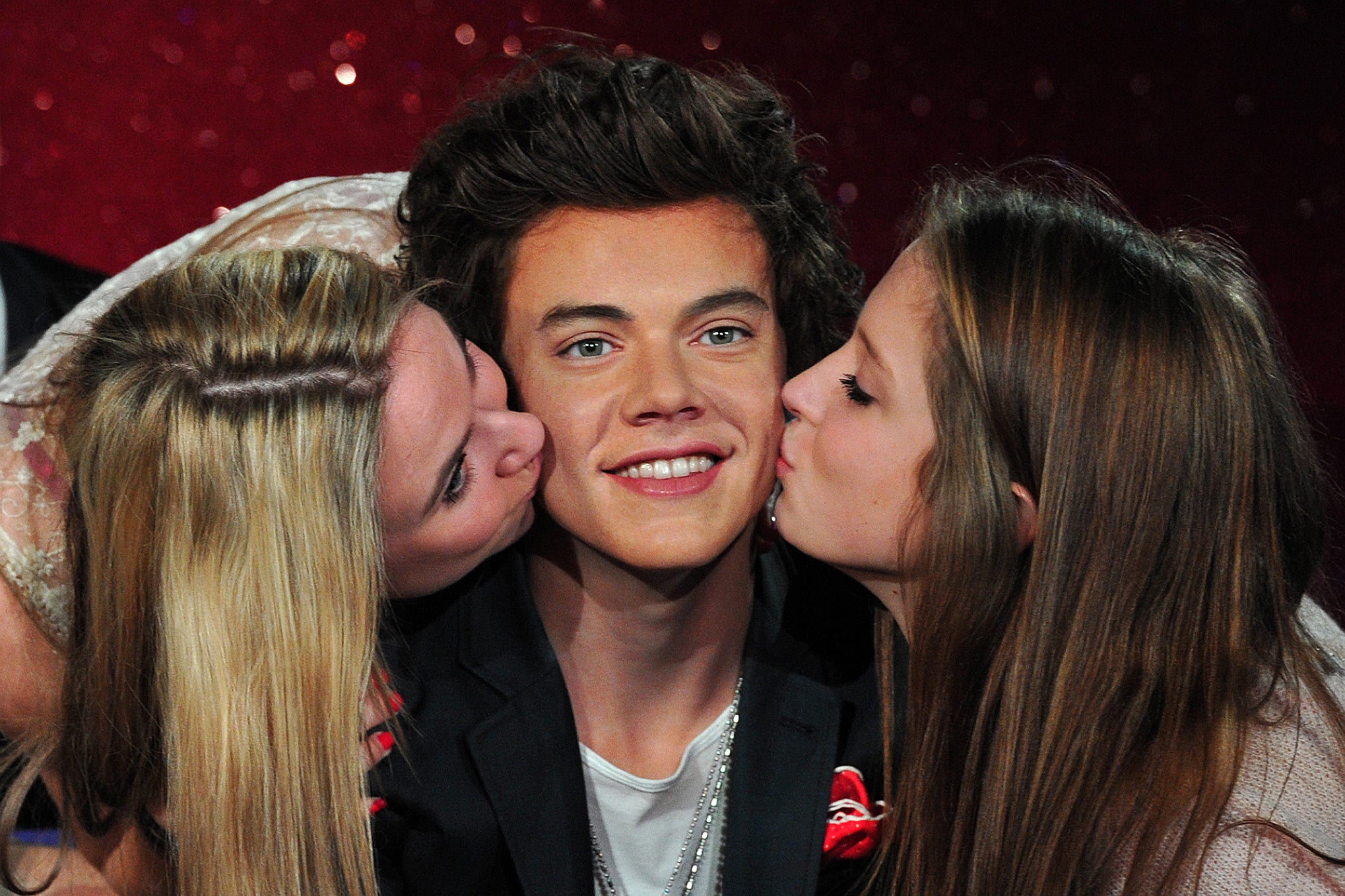 "One Directioners", the name for 1D fans, kiss a waxwork of boy band member Harry Styles at Madame Tussauds