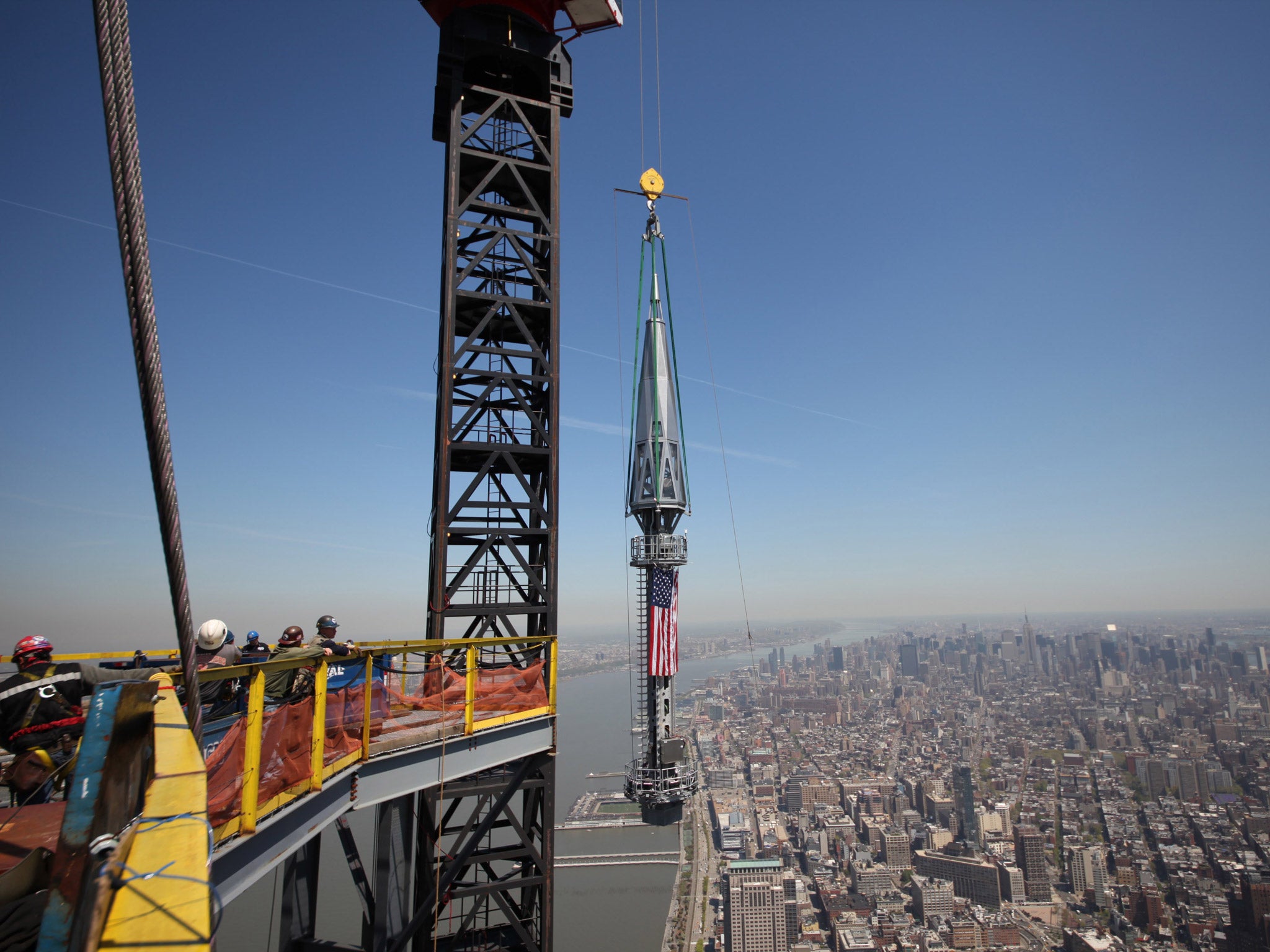 One of the last two segments of the silver spire to be installed on top of One World Trade Center is hoisted to the top of the building