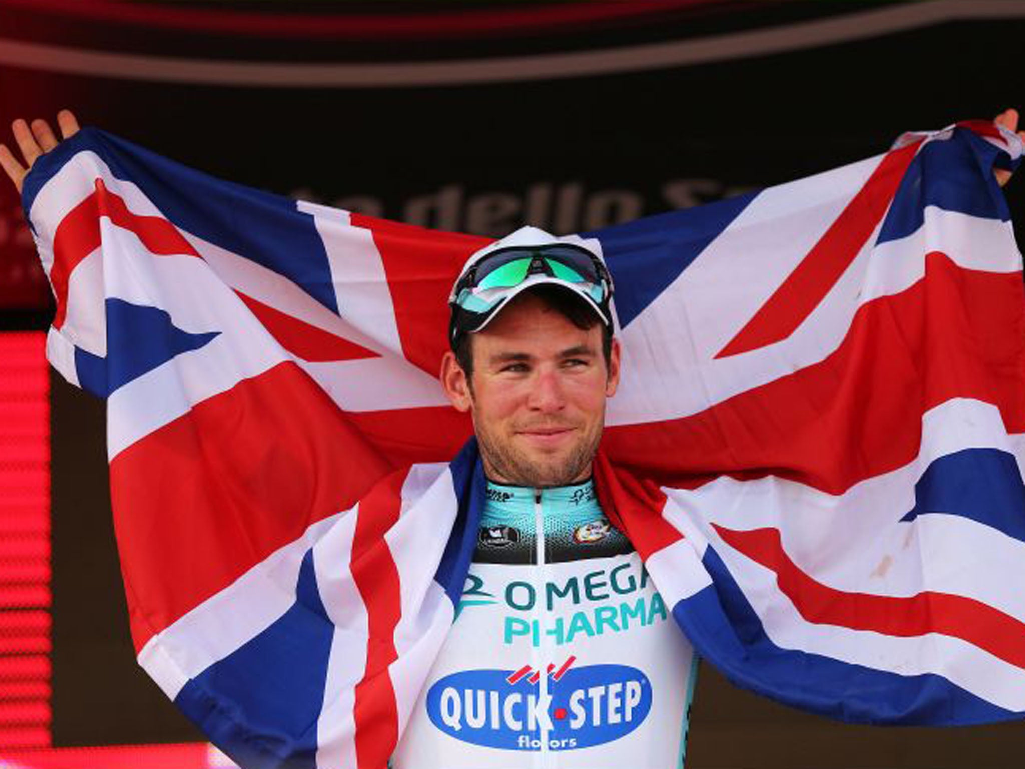 Mark Cavendish poses with a Union Jack on the podium as he celebrates his stage victory