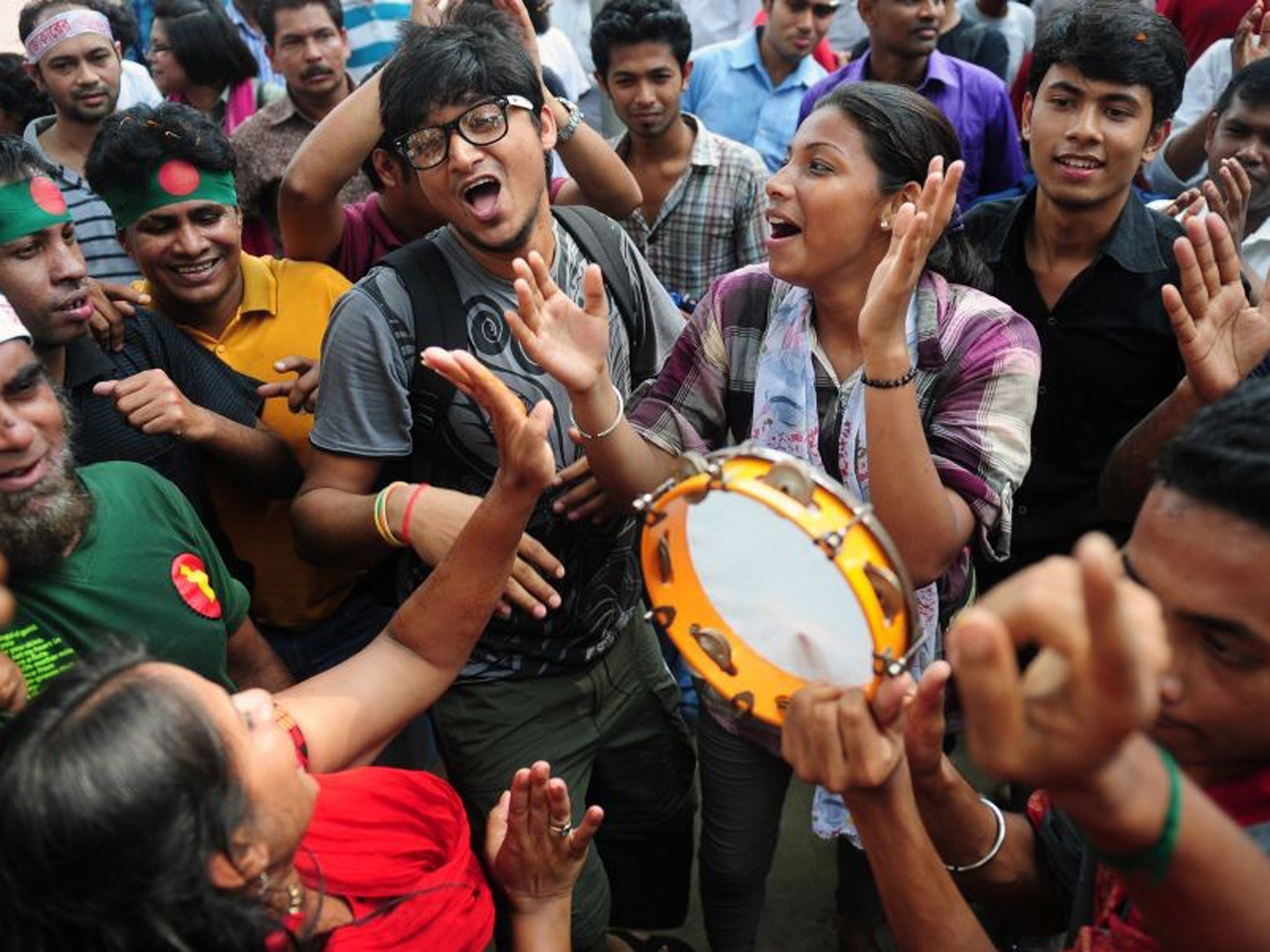 Bangladeshi social activists raise their hands in celebration after hearing the International Crimes Tribunal's guilty verdict on Muhammad Kamaruzzaman