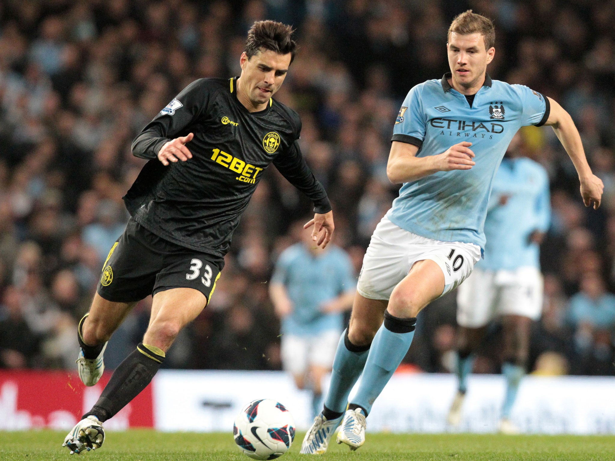 Manchester City's Bosnian striker Edin Dzeko (R) vies with Wigan Athletic's Austrian midfielder Paul Scharner