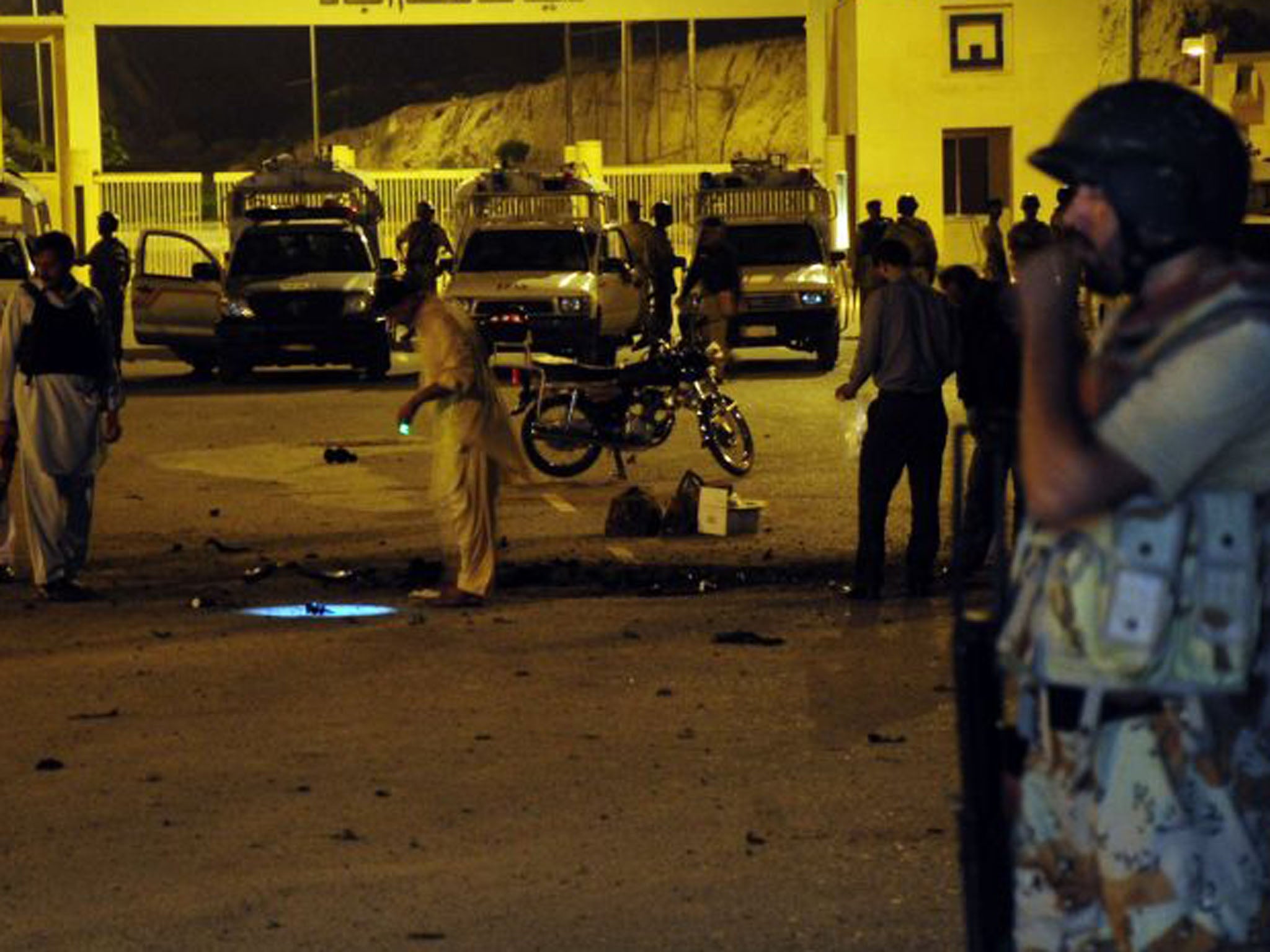 A soldier stands guard as security officials examine the site of a bomb explosion in Karachi, with election day being marred by bombings in in Karachi and Peshawar (Asif Hassan/AFP/Getty Images)