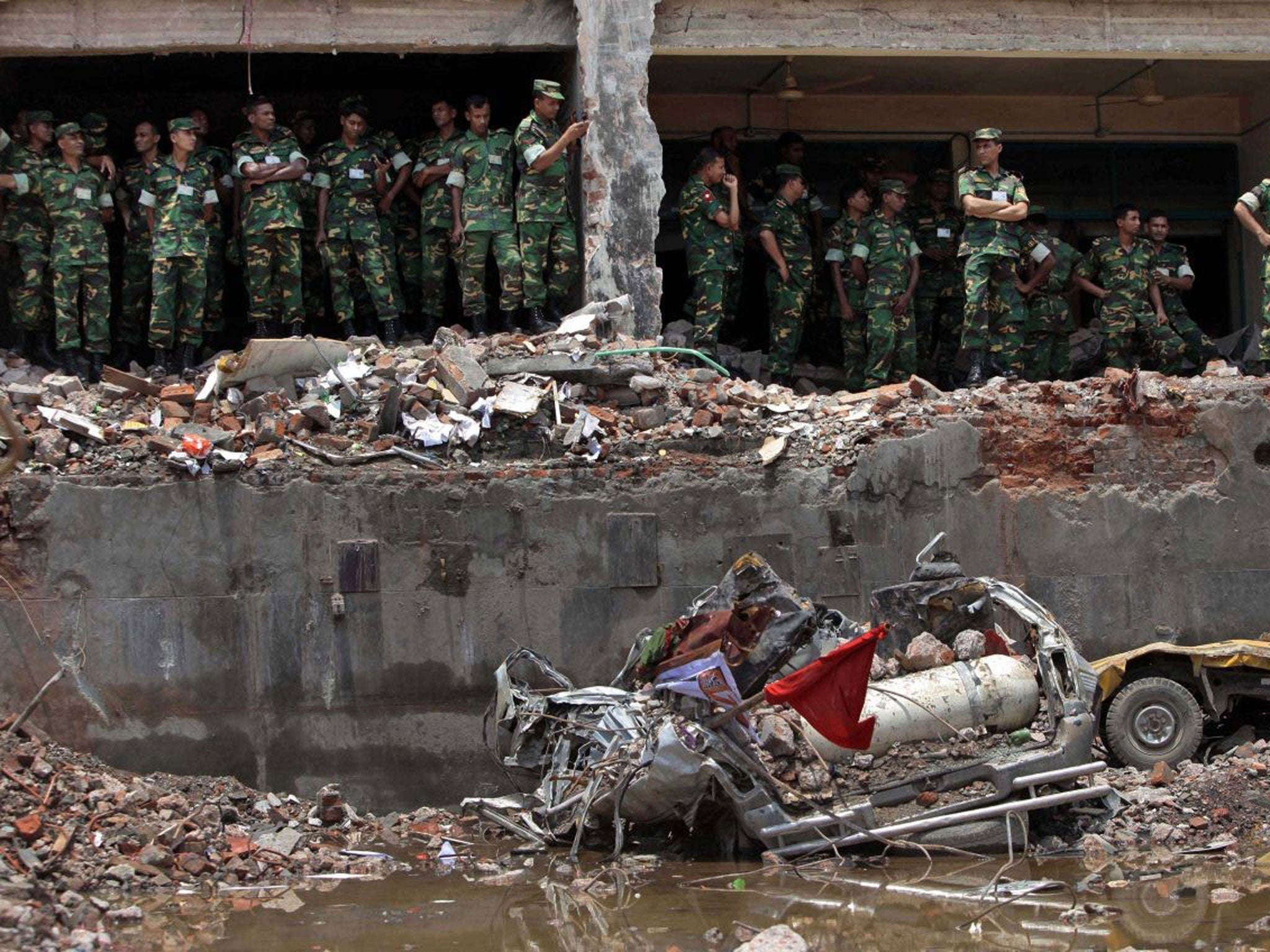 Bangladesh army soldiers stand at the wreckage of a Bangladeshi garment factory building to offer prayers for the souls of the 1,127 people who died in the structure's collapse last month (AP)