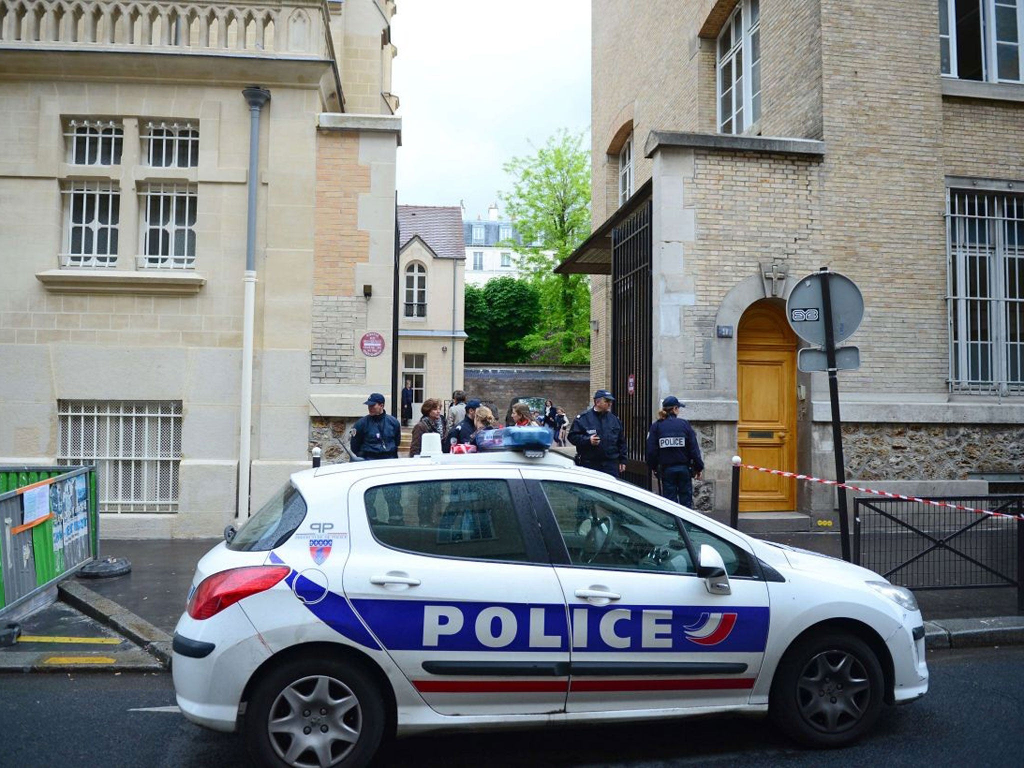 Policemen stand guard at the entrance to a nursery school where a man committed suicide in front of pupils