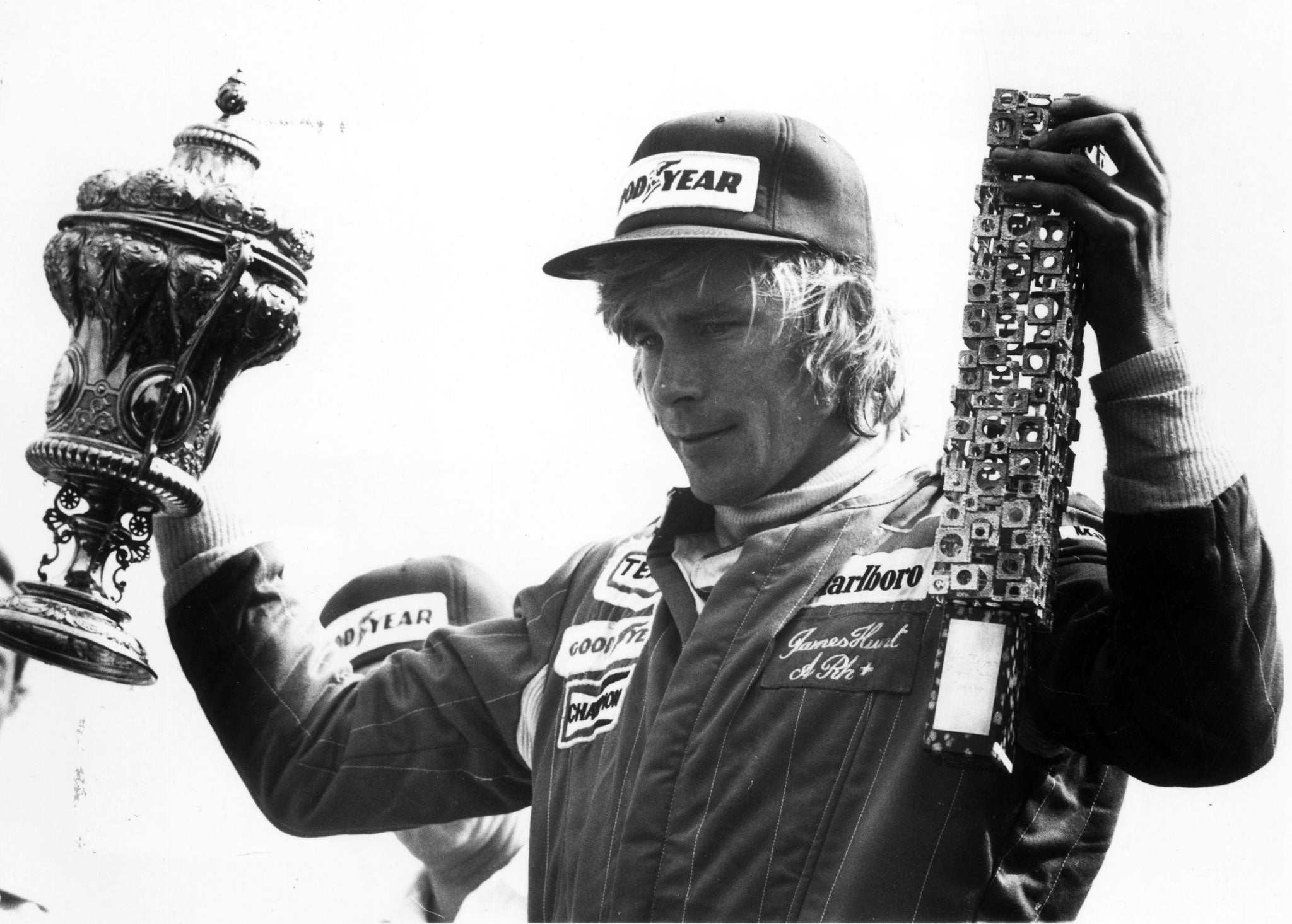 Hunt holds up the winners' trophies after victory in the British Grand Prix at Silverstone in 1977