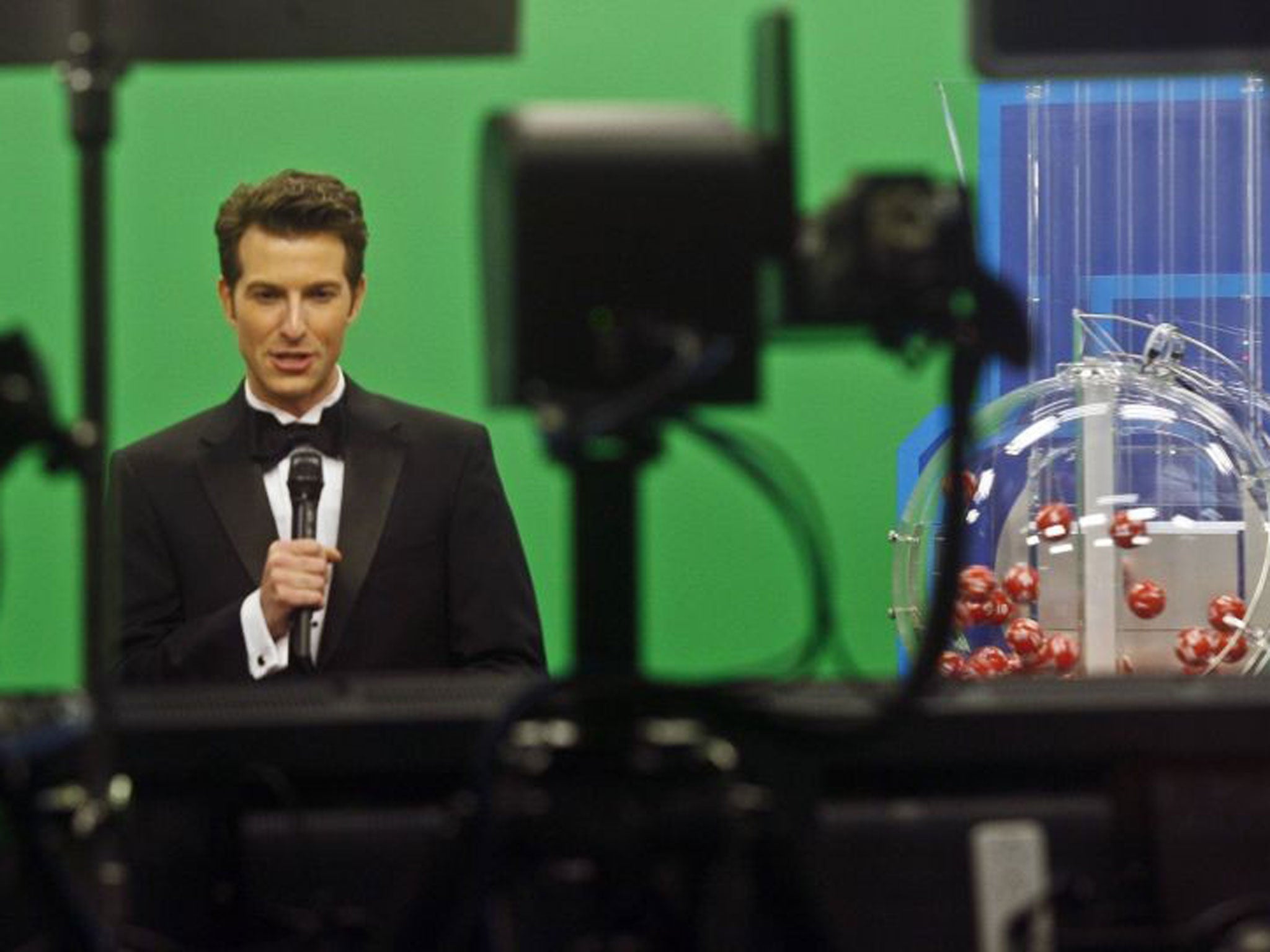 Host Sam Arlen speaks as the Powerball number (R) is about to be chosen at the Florida Lottery studio in Tallahassee May 18, 2013. The winning numbers are 22, 10, 13, 14, 52, and the Powerball number is 11. The Powerball jackpot is a record-setting $590.5