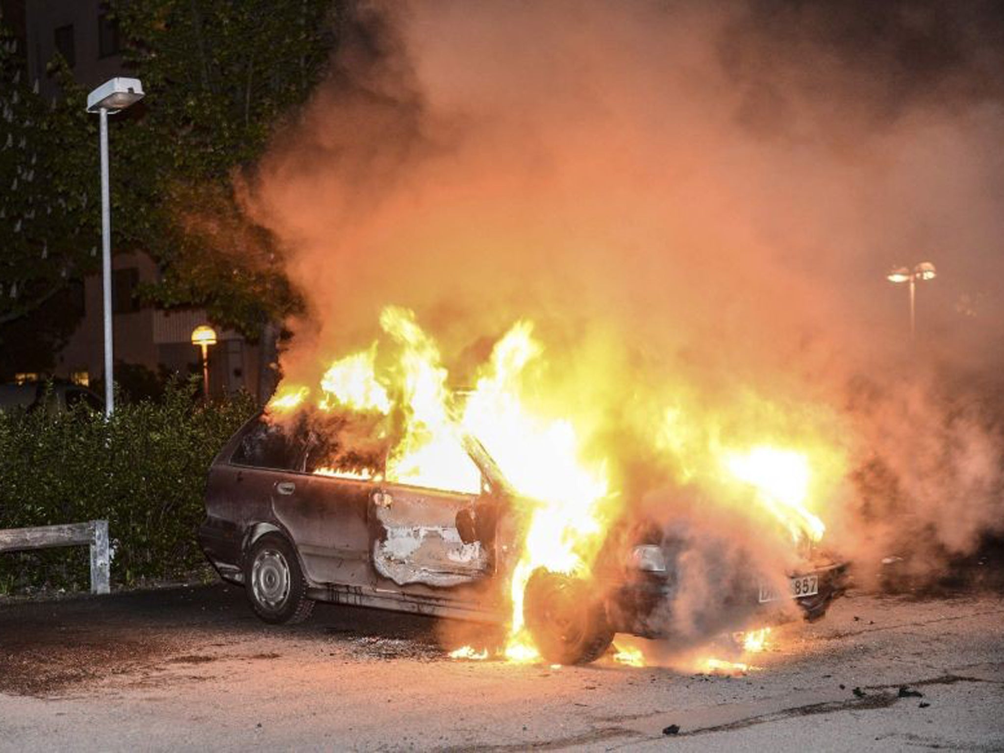 A car set on fire burns, following riots in the Stockholm suburb of Kista