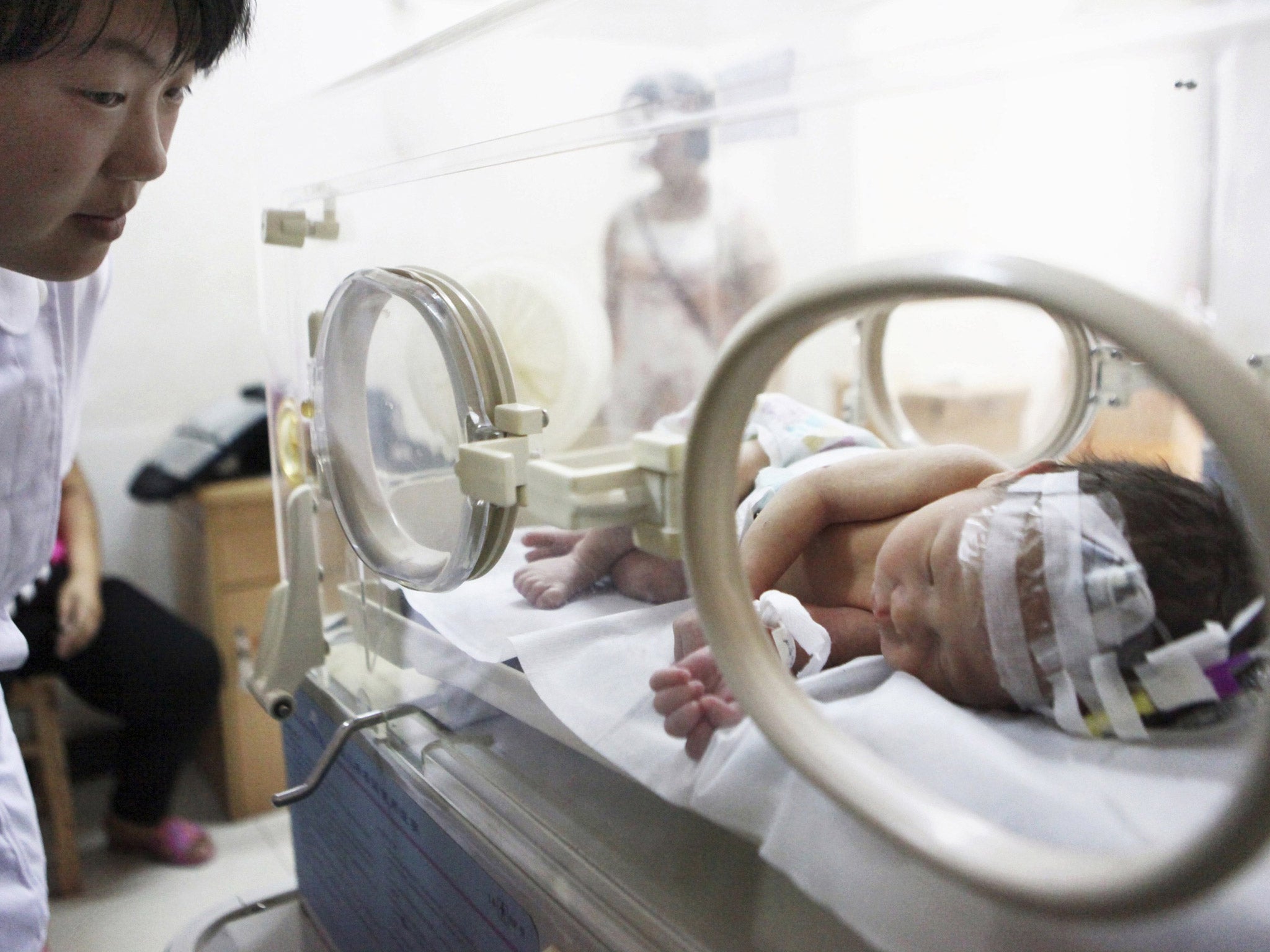 A nurse looks at the abandoned newborn baby resting in an incubator after he was rescued from a sewage pipe at a hospital in Jinhua, Zhejiang province. Firefighters in eastern China rescued the abandoned newborn baby boy lodged in a sewage pipe directly b