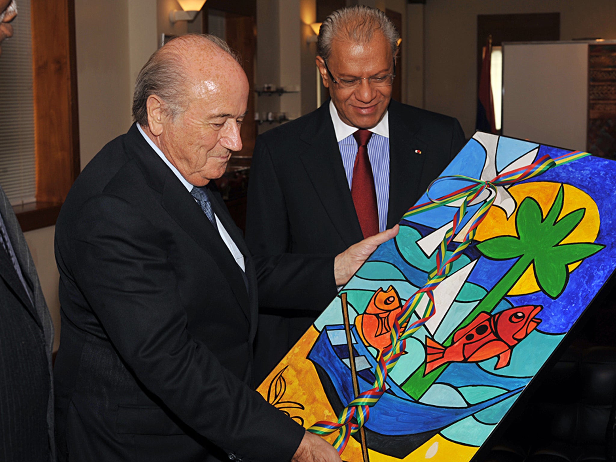 The President of FIFA, Sepp Blatter (L) holds up a painting by Mauritian painter Vaco Baissac