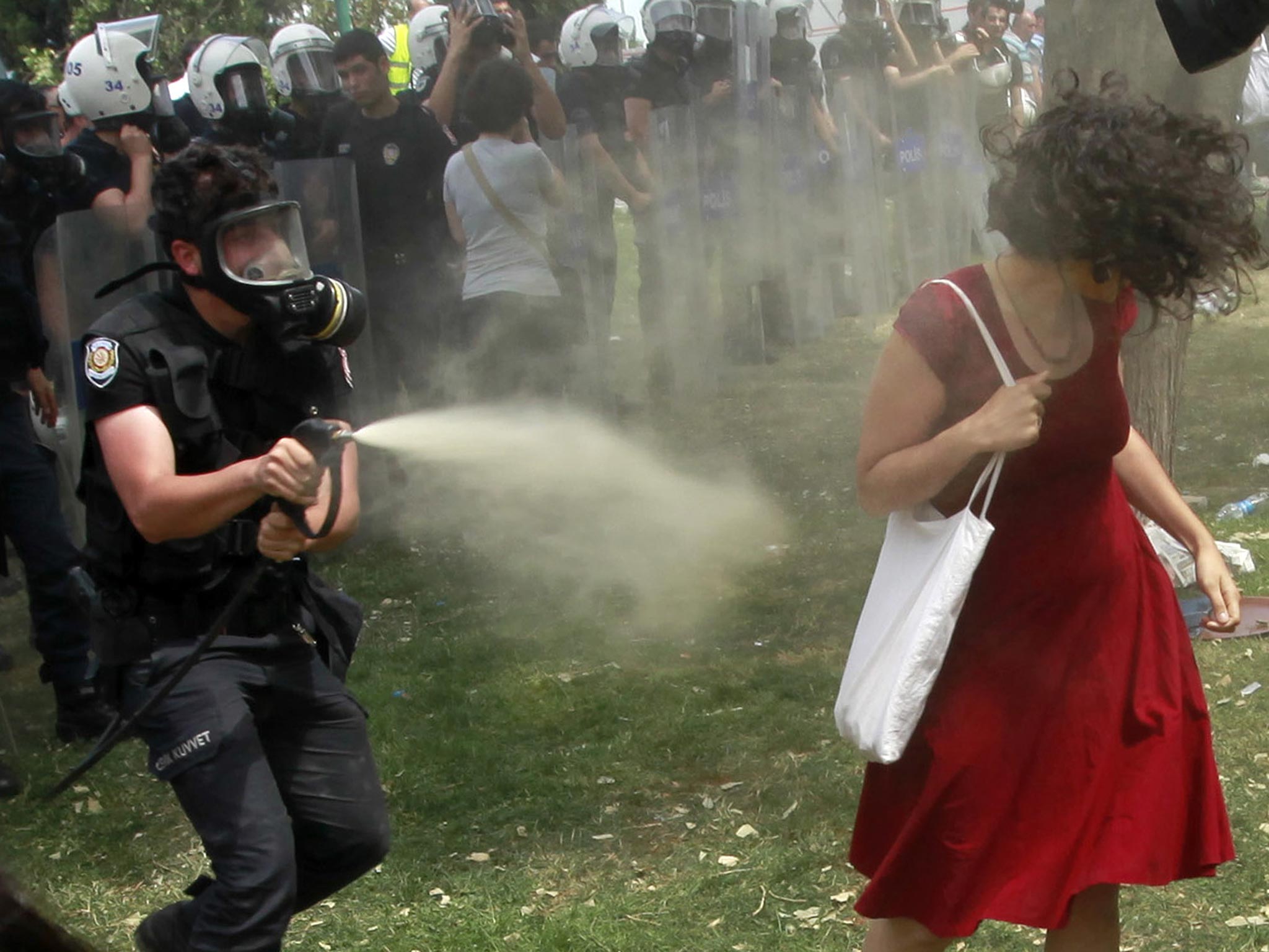 A Turkish riot policeman uses tear gas against a woman as people protest against the destruction of trees in a park brought about by a pedestrian project, in Taksim Square in central Istanbul