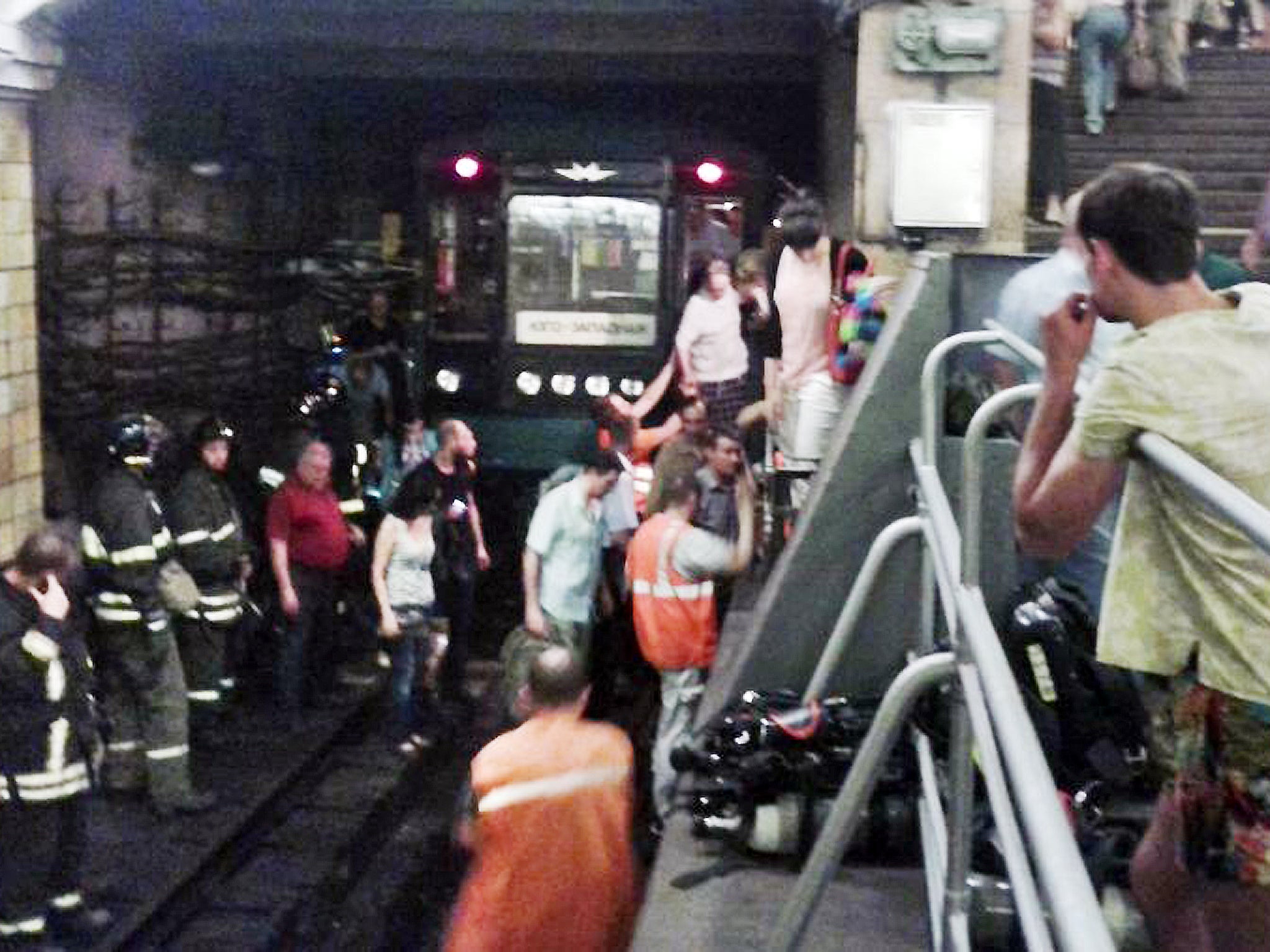 In this image made by a mobile phone camera, people leave a subway station in downtown Moscow after a rush-hour fire in Moscow's Metro