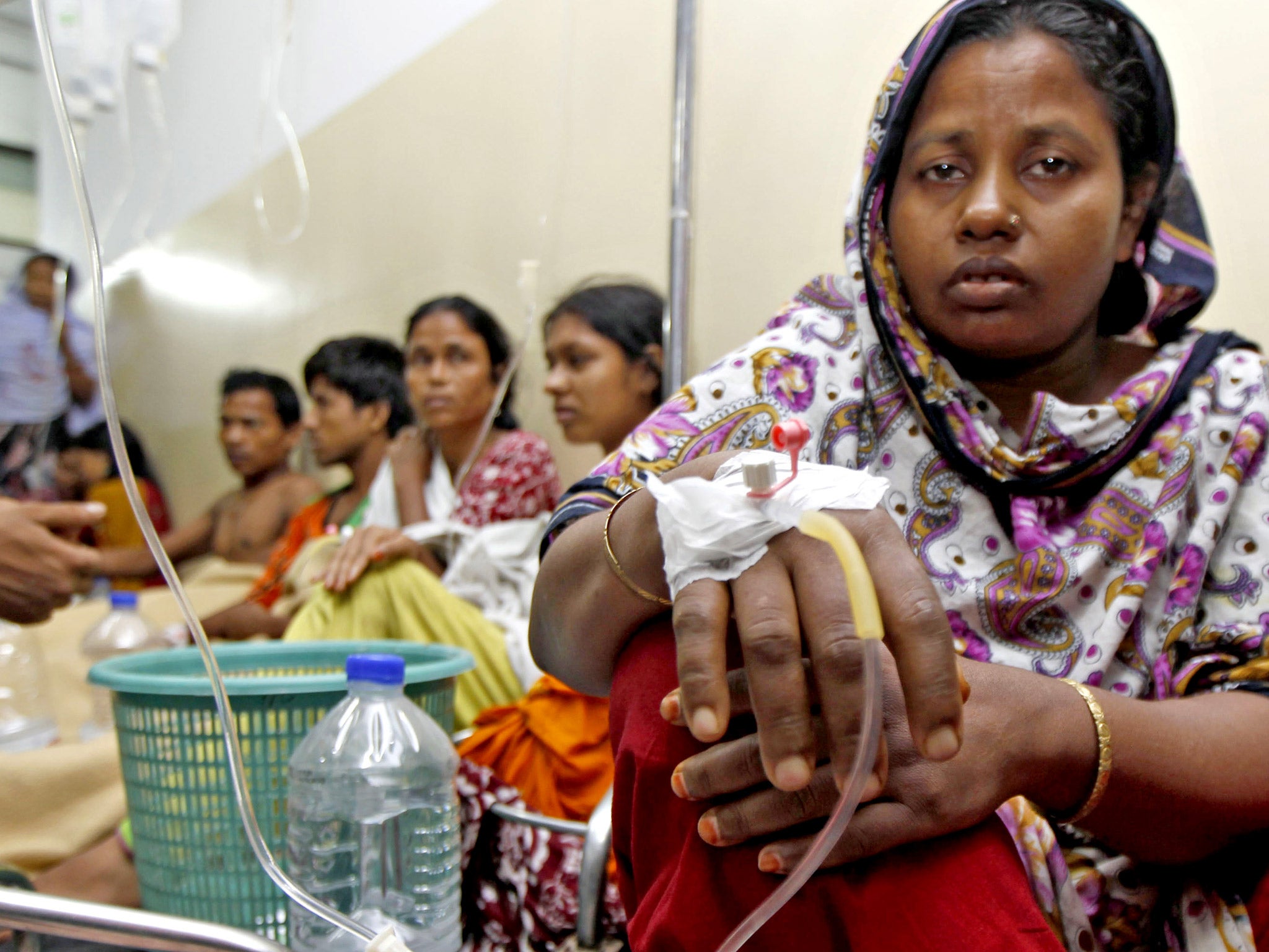 Factory workers rest on the floor as they receive intravenous drips after falling sick from drinking contaminated water