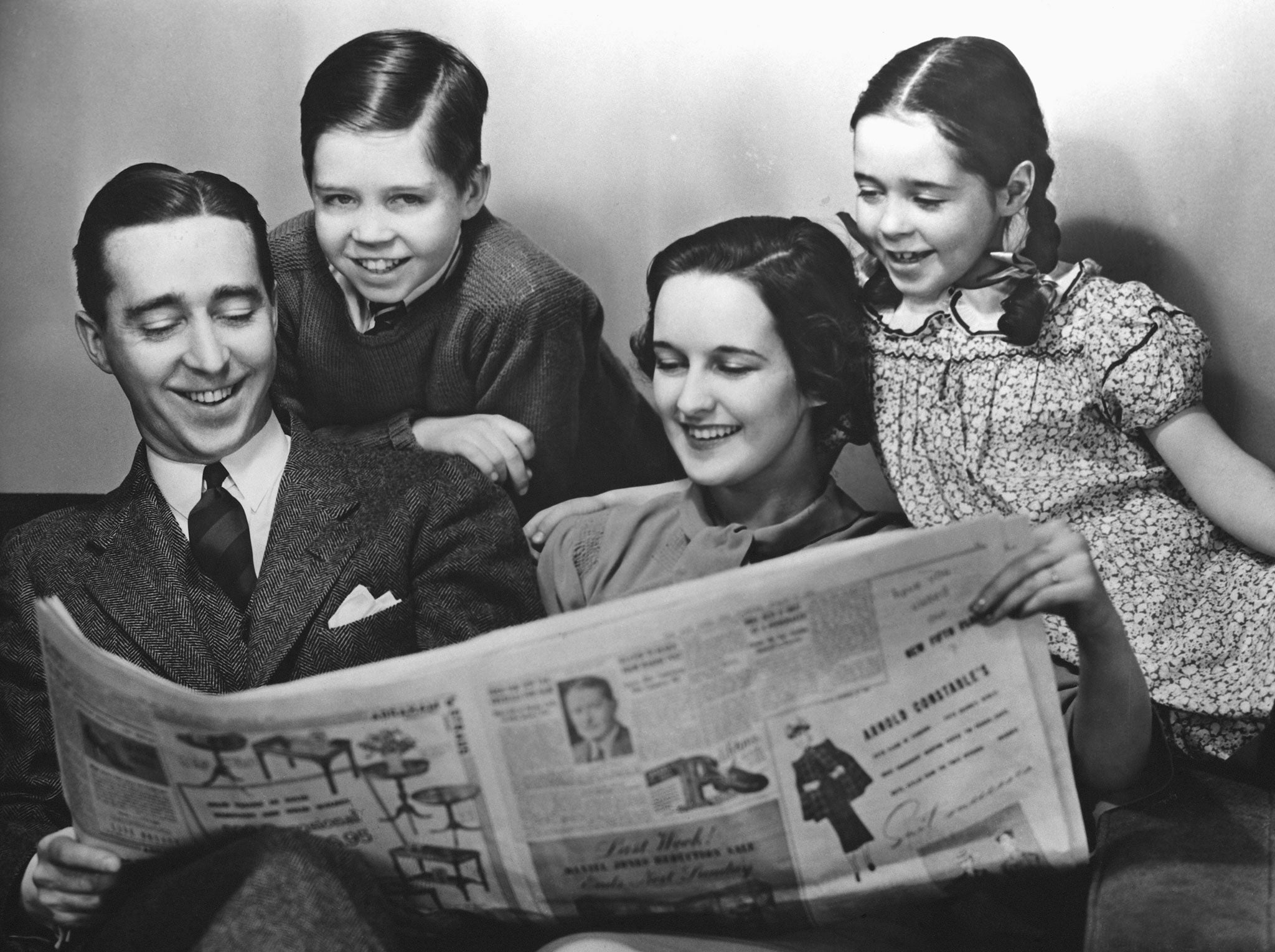 An American family reading a newspaper circa 1950