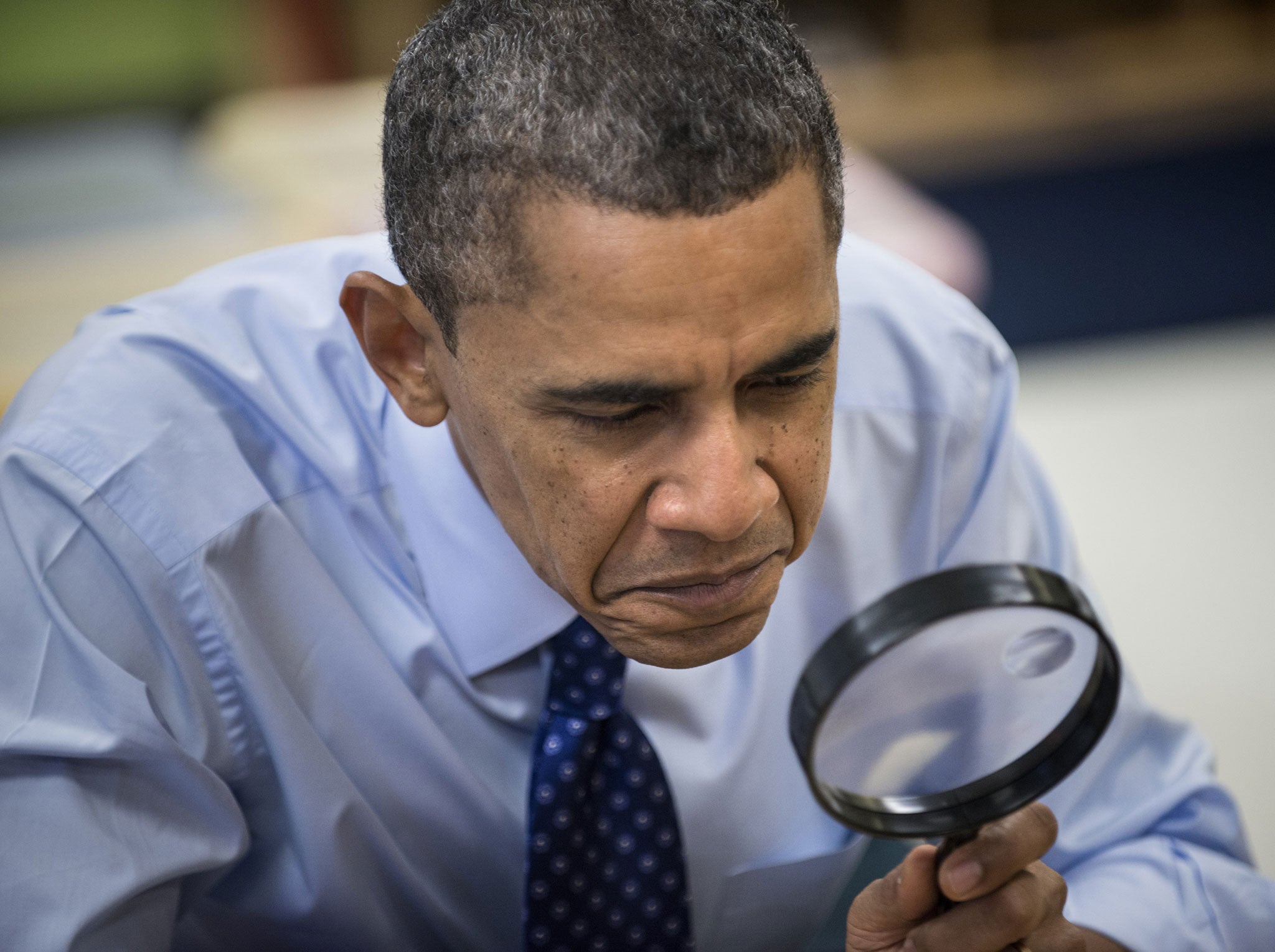 US President Barack Obama uses a magnifying glass while he plays a learning game while visiting children at College Heights Early Childhood Learning Center February 14, 2013 in Decatur, Georgia.