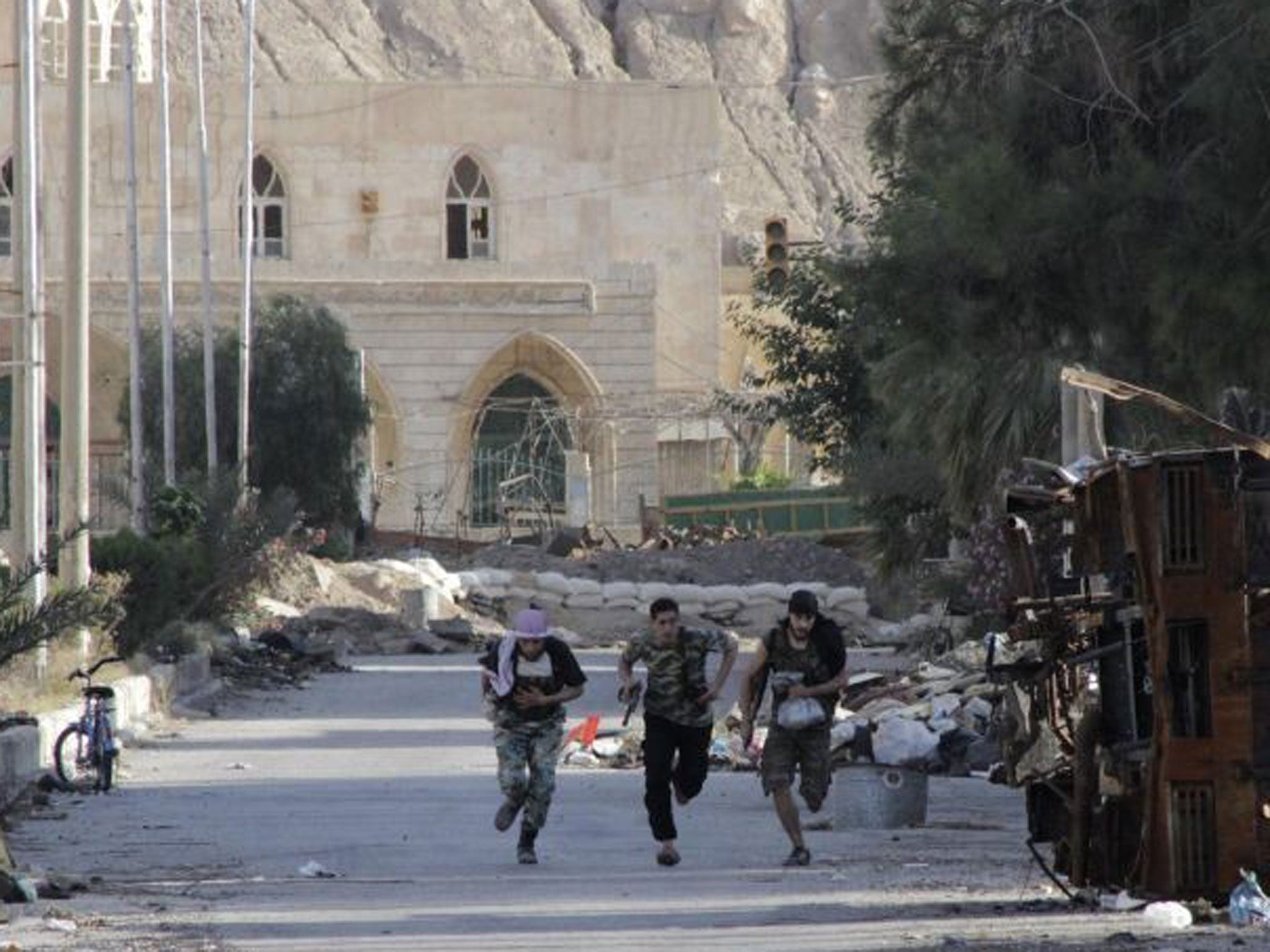 Members of the Free Syrian Army run to avoid a sniper in Deir al-Zor