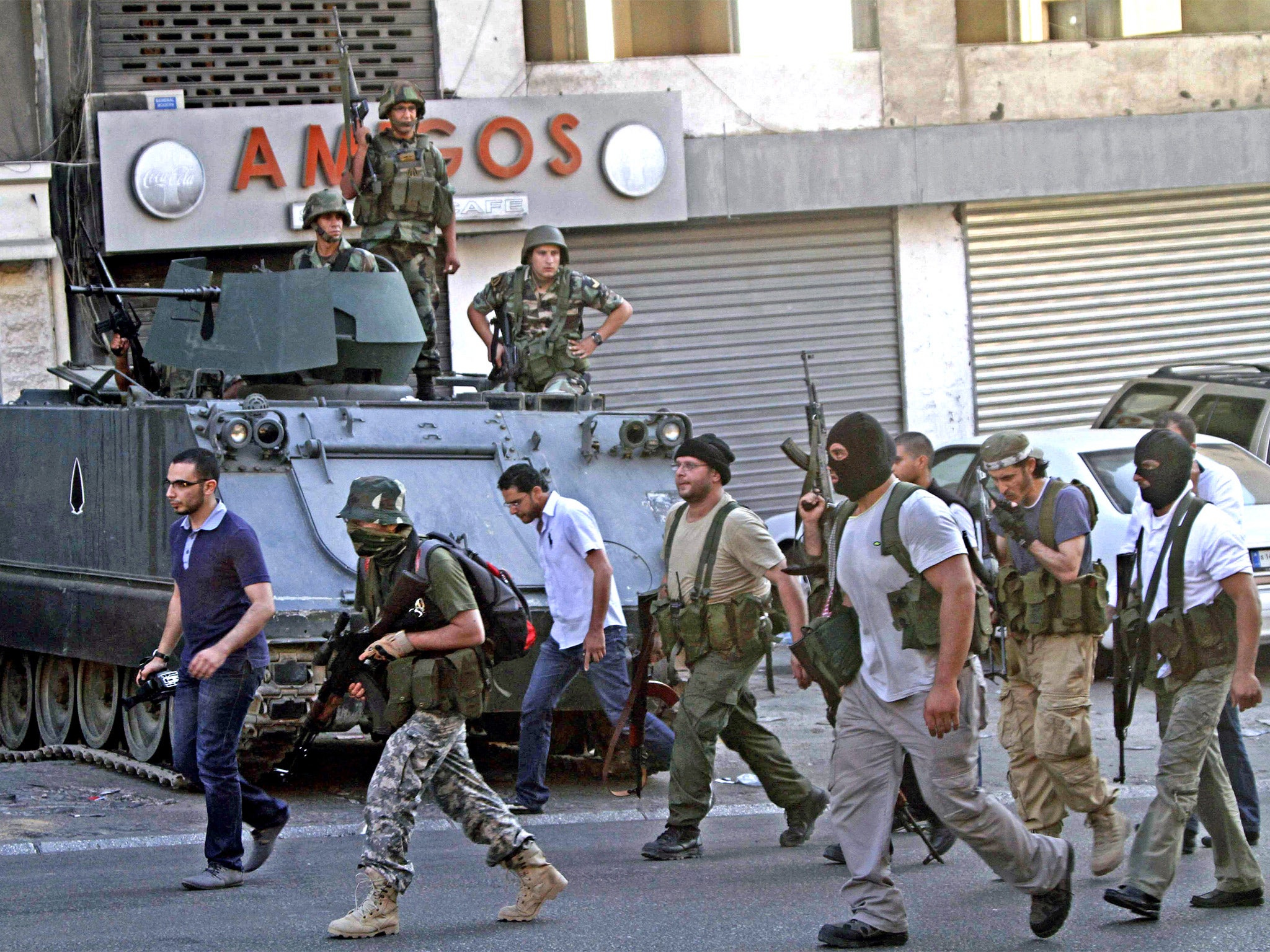 Gunmen and followers of hardline Sunni cleric Sheik Ahmad al-Assir pass in front of Lebanese army soldiers in the southern port city of Sidon