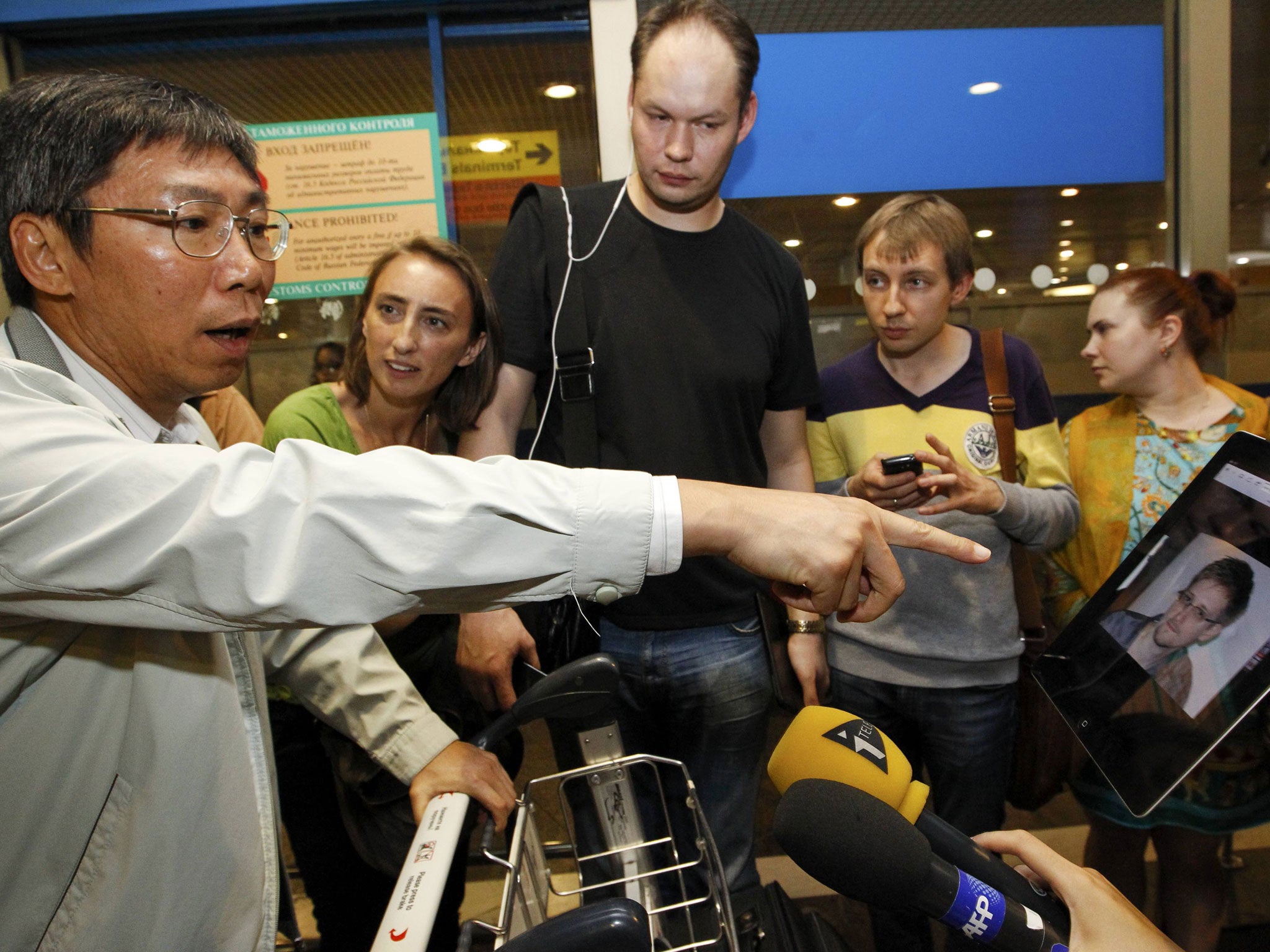 Journalists show an iPad with the picture of Edward Snowden, former contractor for the U.S. National Security Agency, to passengers of a flight from Hong Kong trying to find out if Snowden was aboard the plane, in Moscow's Sheremetyevo airport