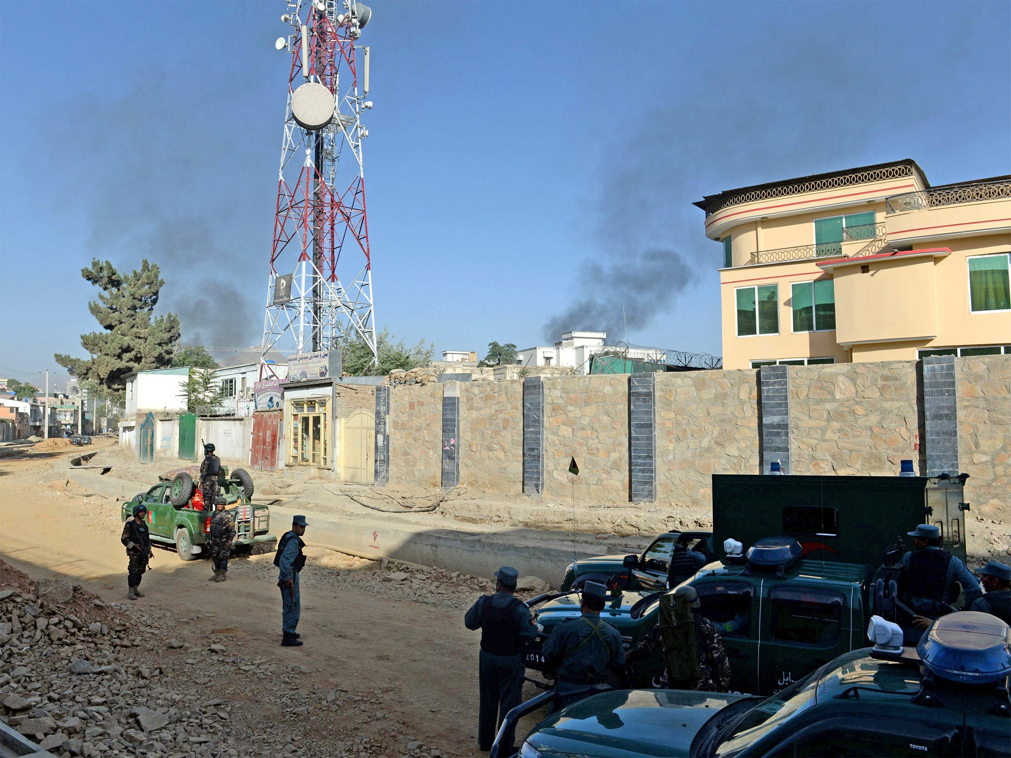 Afghan security forces stand guard as smoke rises from the entrance gate of the Presidential palace in Kabul