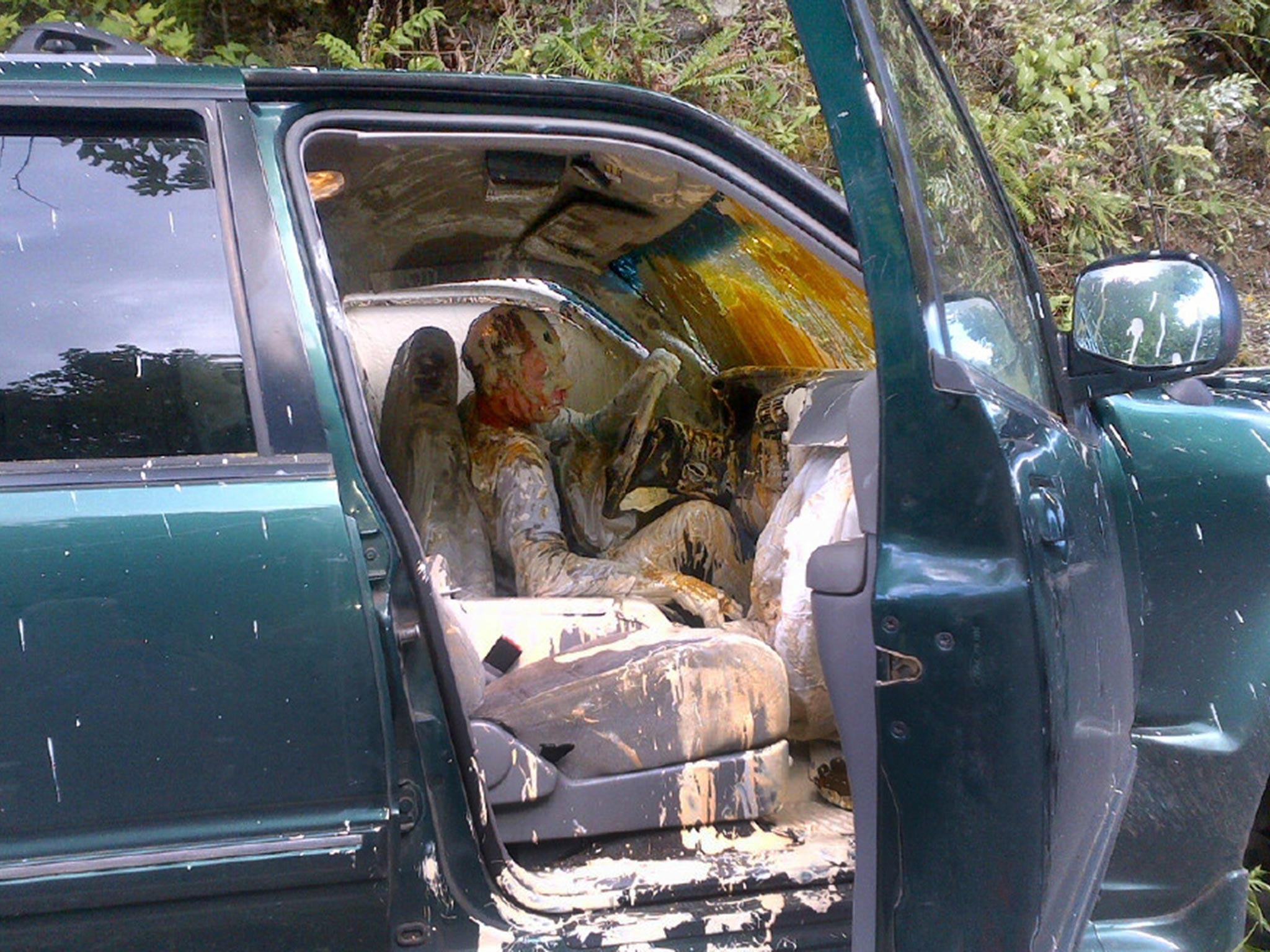 An unidentified man sits covered in paint as he waits to be removed from his vehicle after it went off the road and crashed near Belfair, Washington