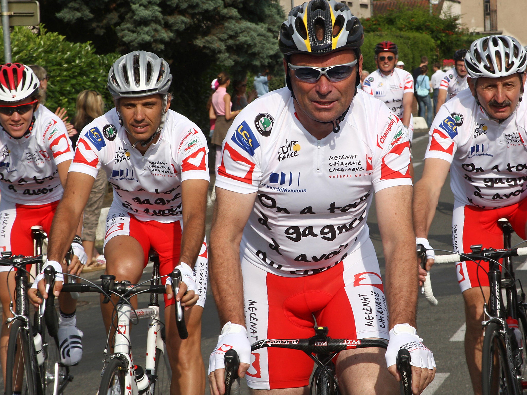 Five-time Tour de France winner Bernard Hinault (C) rides in front of (from L) French actress Adeline Blondeau, French car racer Paul Belmondo during 'L'etape du Tour'