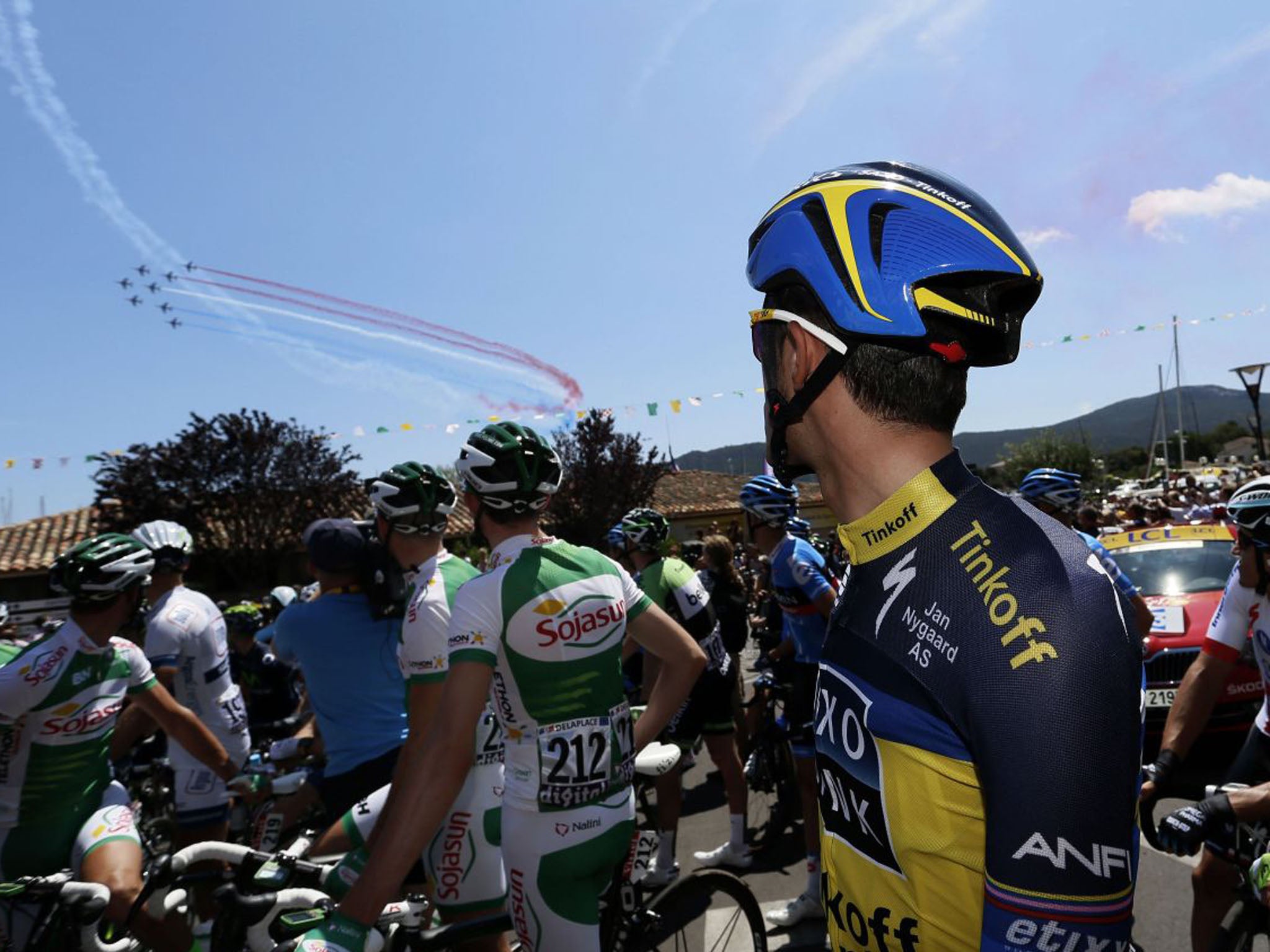 Spain's Alberto Contador looks at jets from the French Air Force precision flying team "La Patrouille de France" performing above Porto-Vecchio before the start of the stage