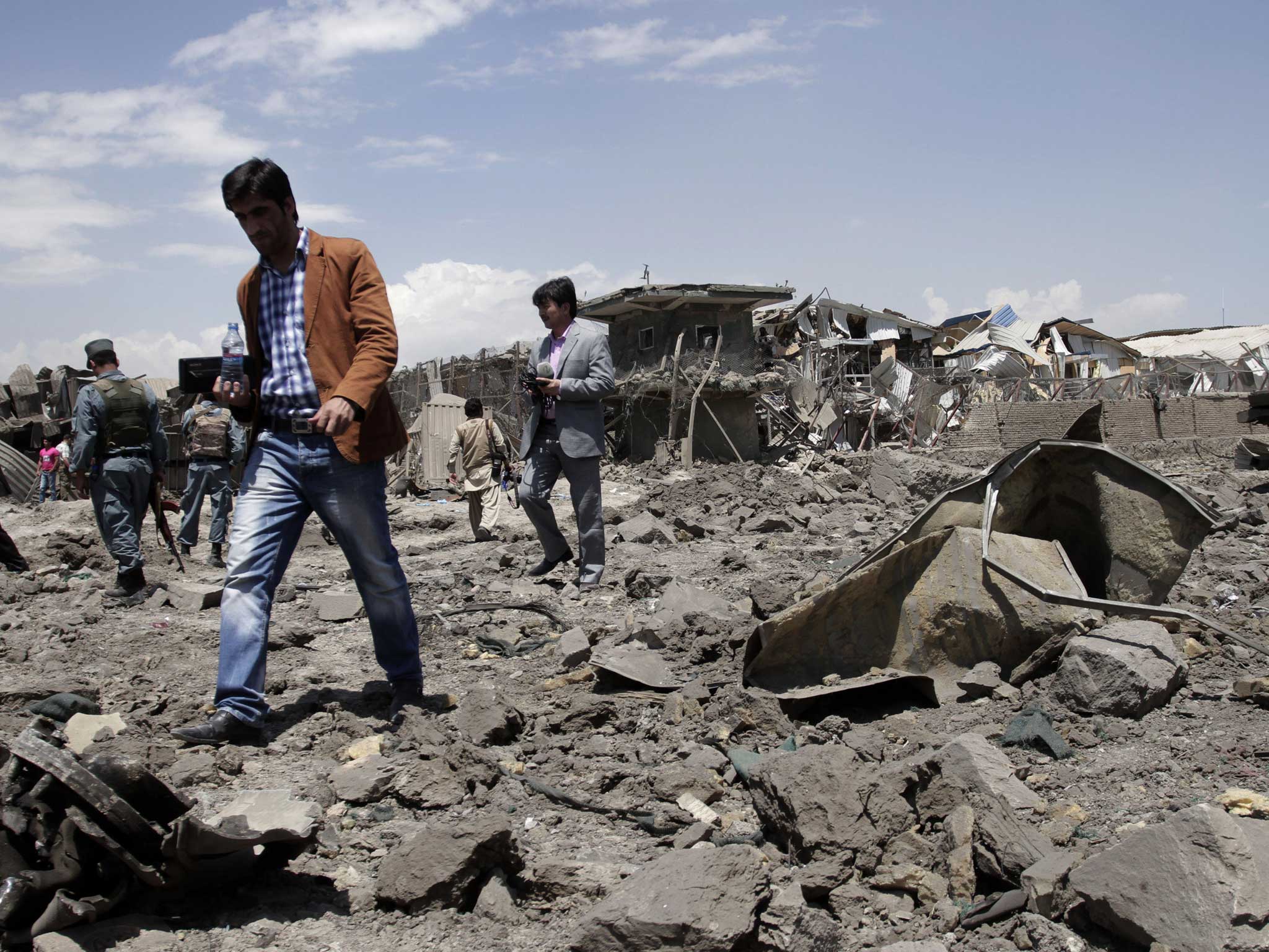 Afghan security personnel examine the site of the suicide car bombing