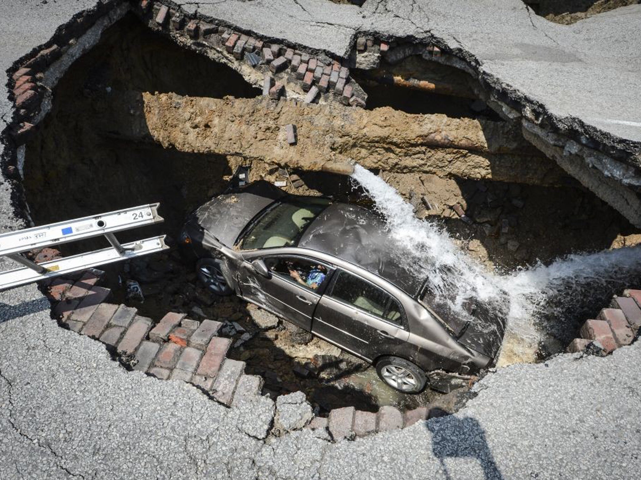 This photo provided by the Toledo, Ohio Fire and Rescue Department shows Pamela Knox's car at the bottom of a sinkhole caused by a broken water pipe in Toledo, Ohio