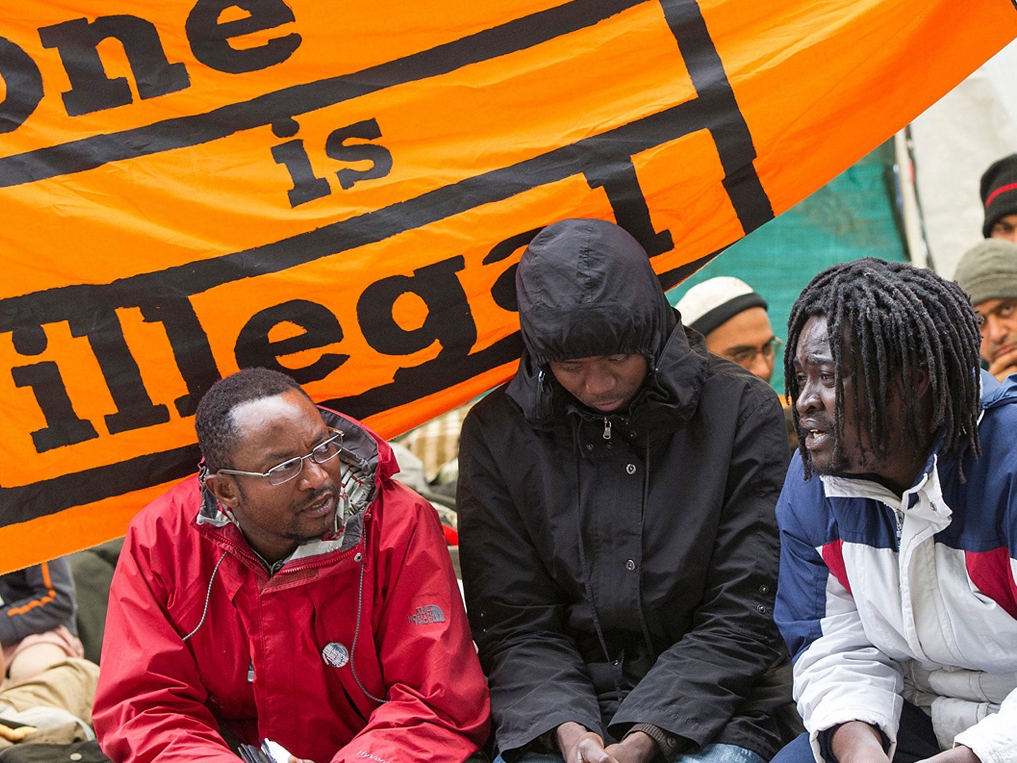 Asylum seekers sit in an outdoor camp in Munich