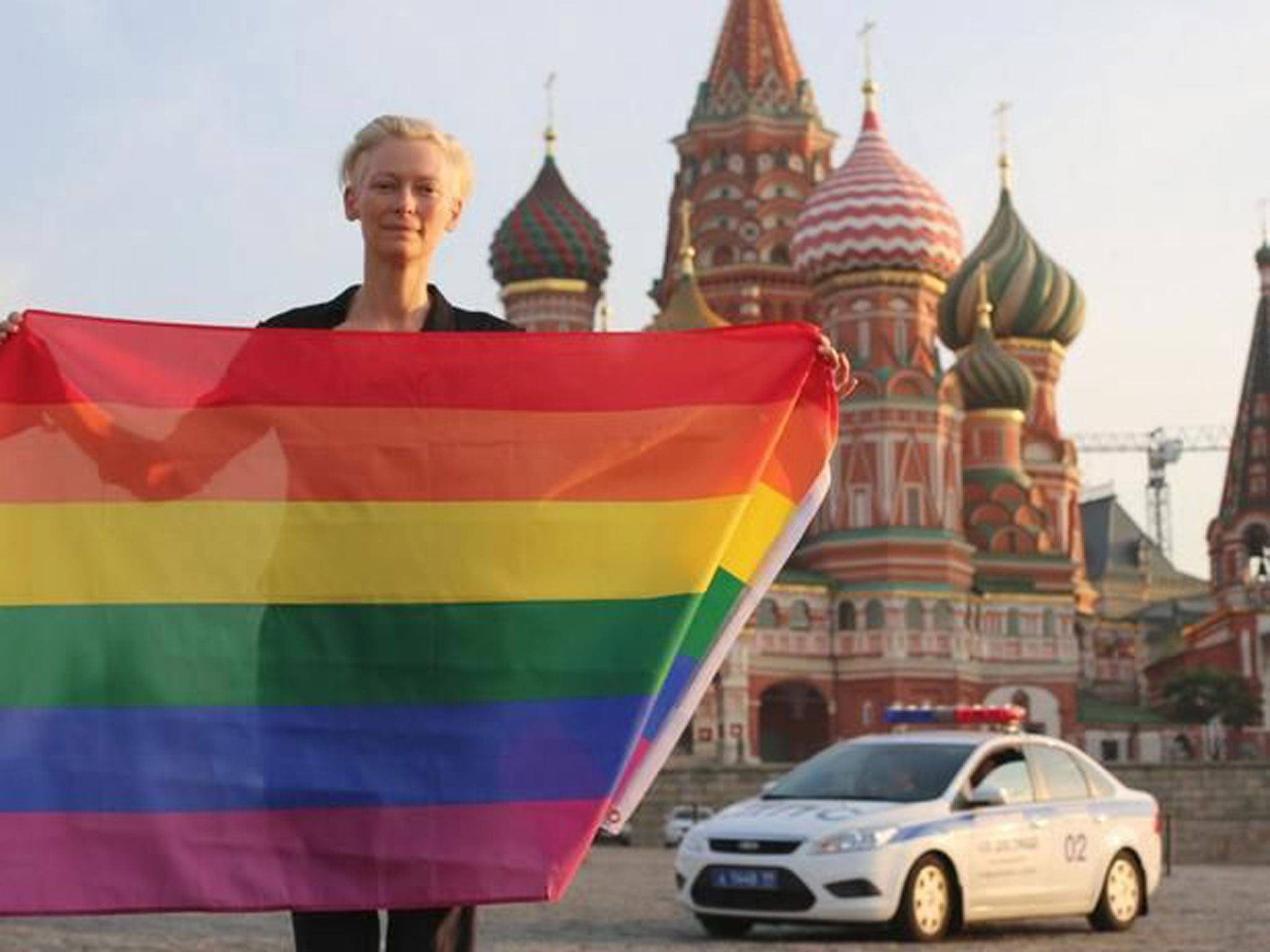 Actress Tilda Swinton posing in Red Square with a rainbow flag in July