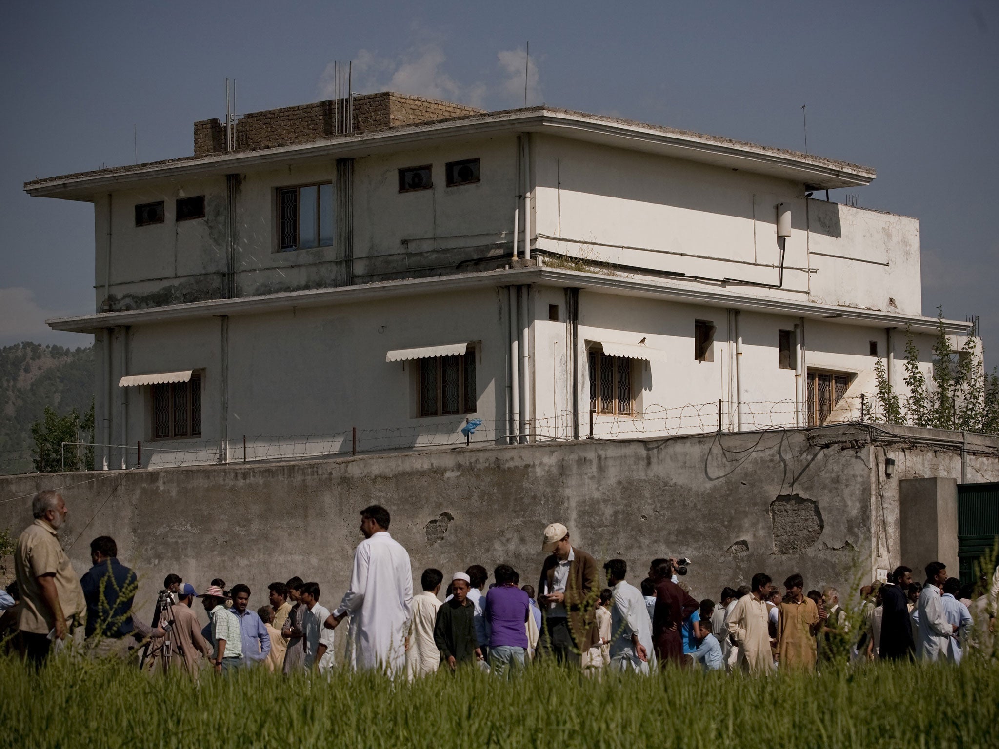 Locals and media gather outside the compound, pictured in May 2011, where Osama Bin Laden was reportedly killed in an operation by US Navy Seals