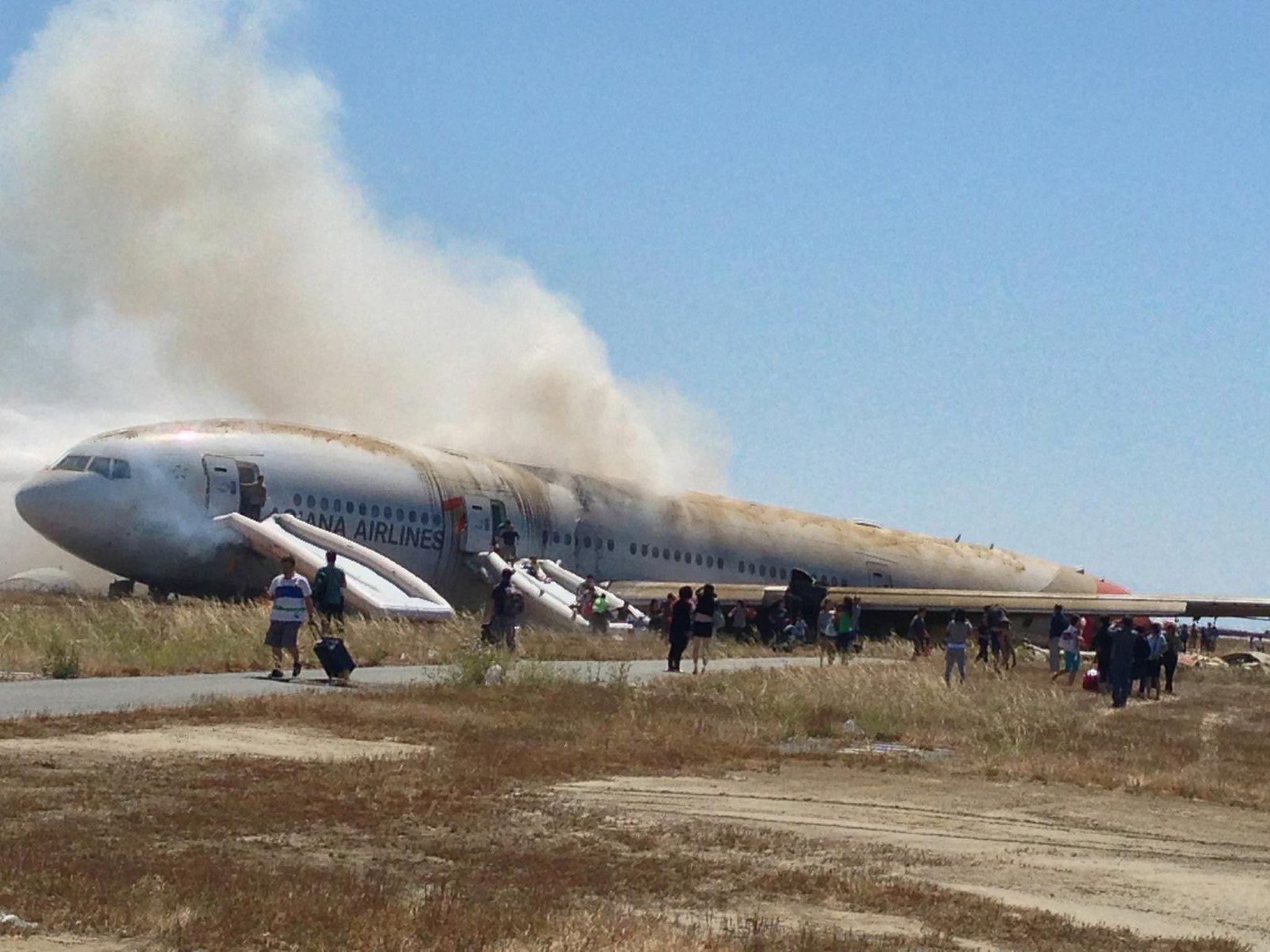 Passengers walk away from Asiana Airlines Boeing 777 aircraft after a crash landing at San Francisco International Airport in San Francisco