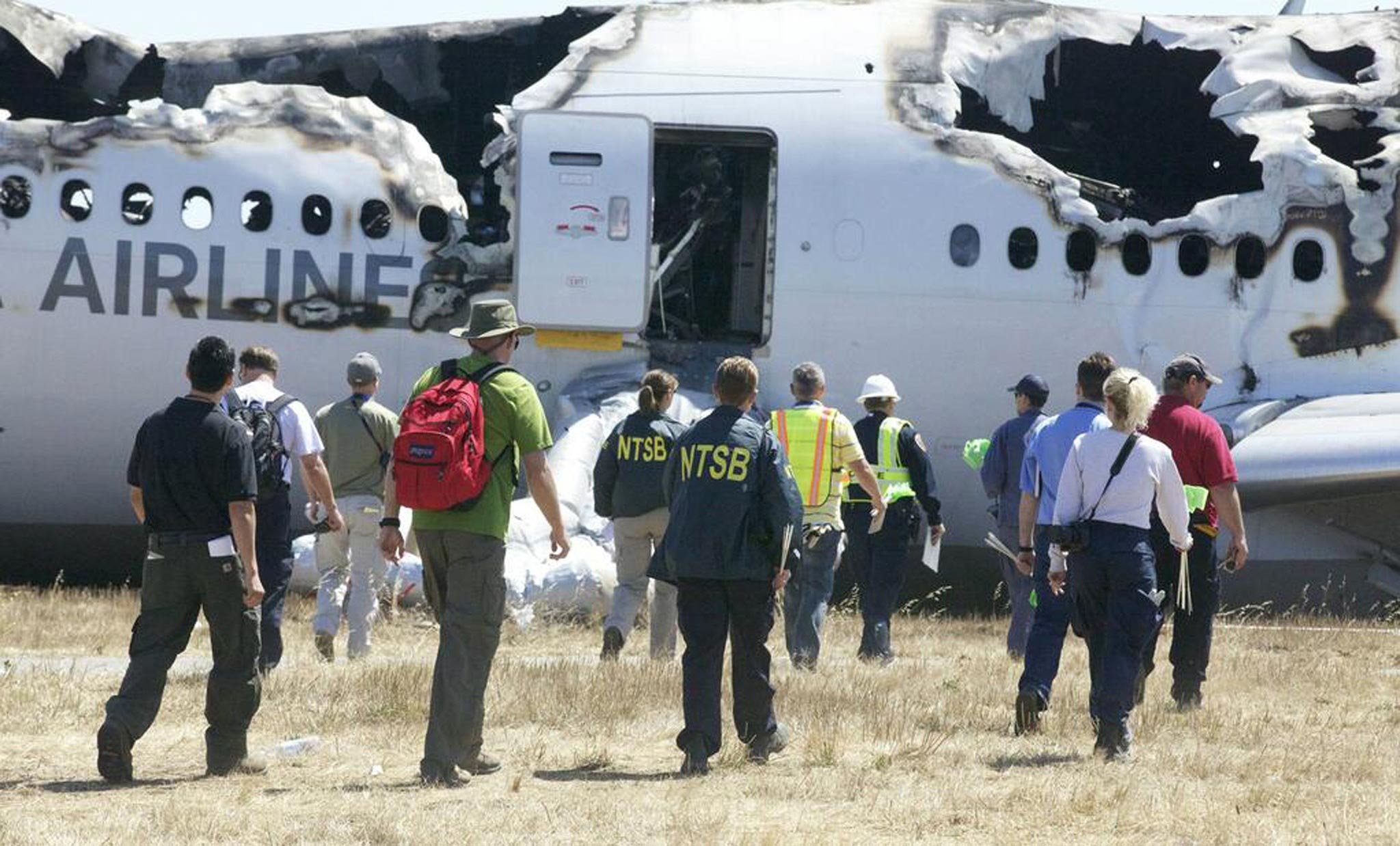 U.S. National Transportation Safety Board (NTSB) investigators work at the scene of the Asiana Airlines Flight 214 crash site at San Francisco International Airport in San Francisco, California