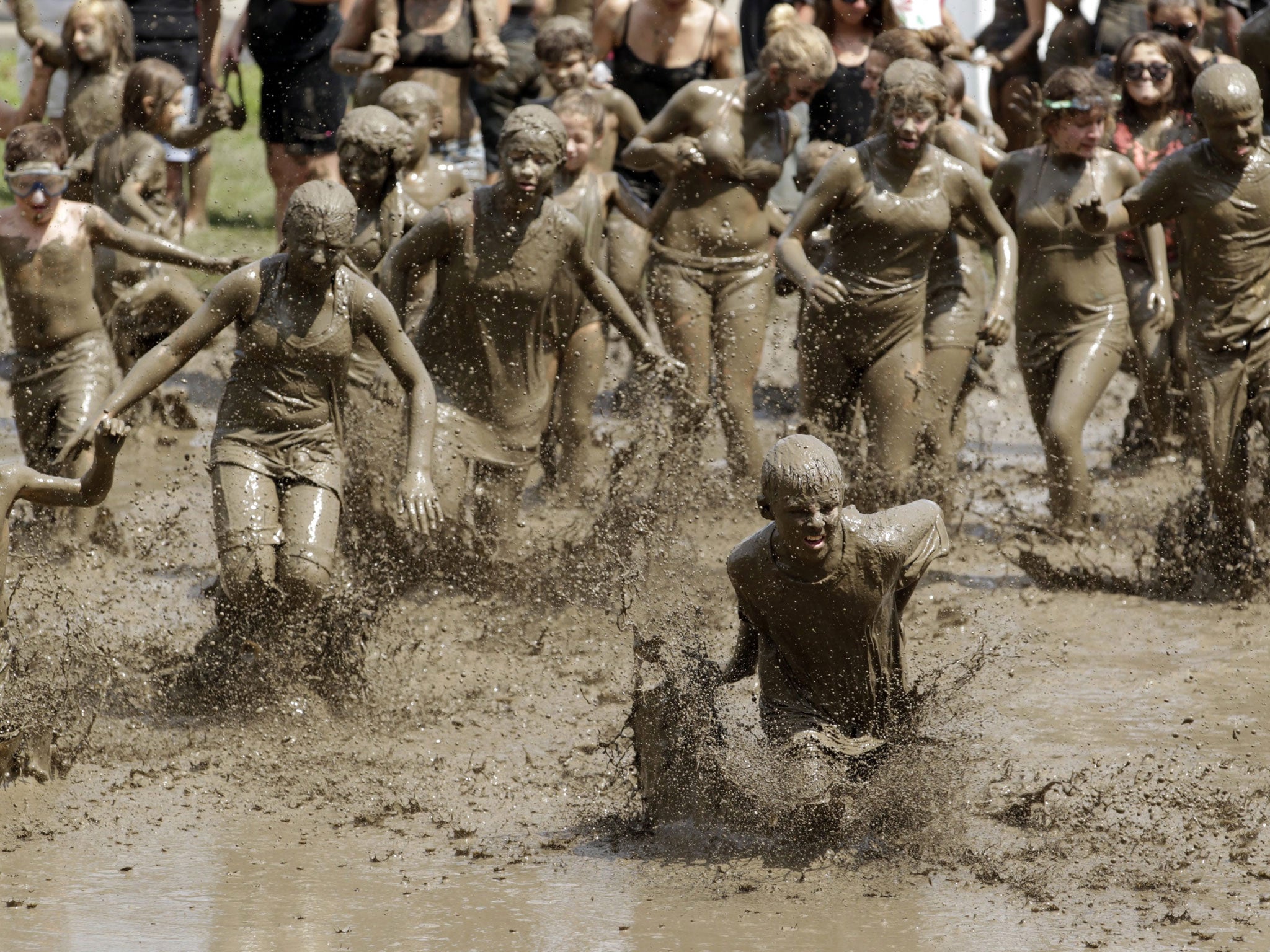 Kids run in to the mud pit during the 26th annual Mud Day in Westland, Michigan