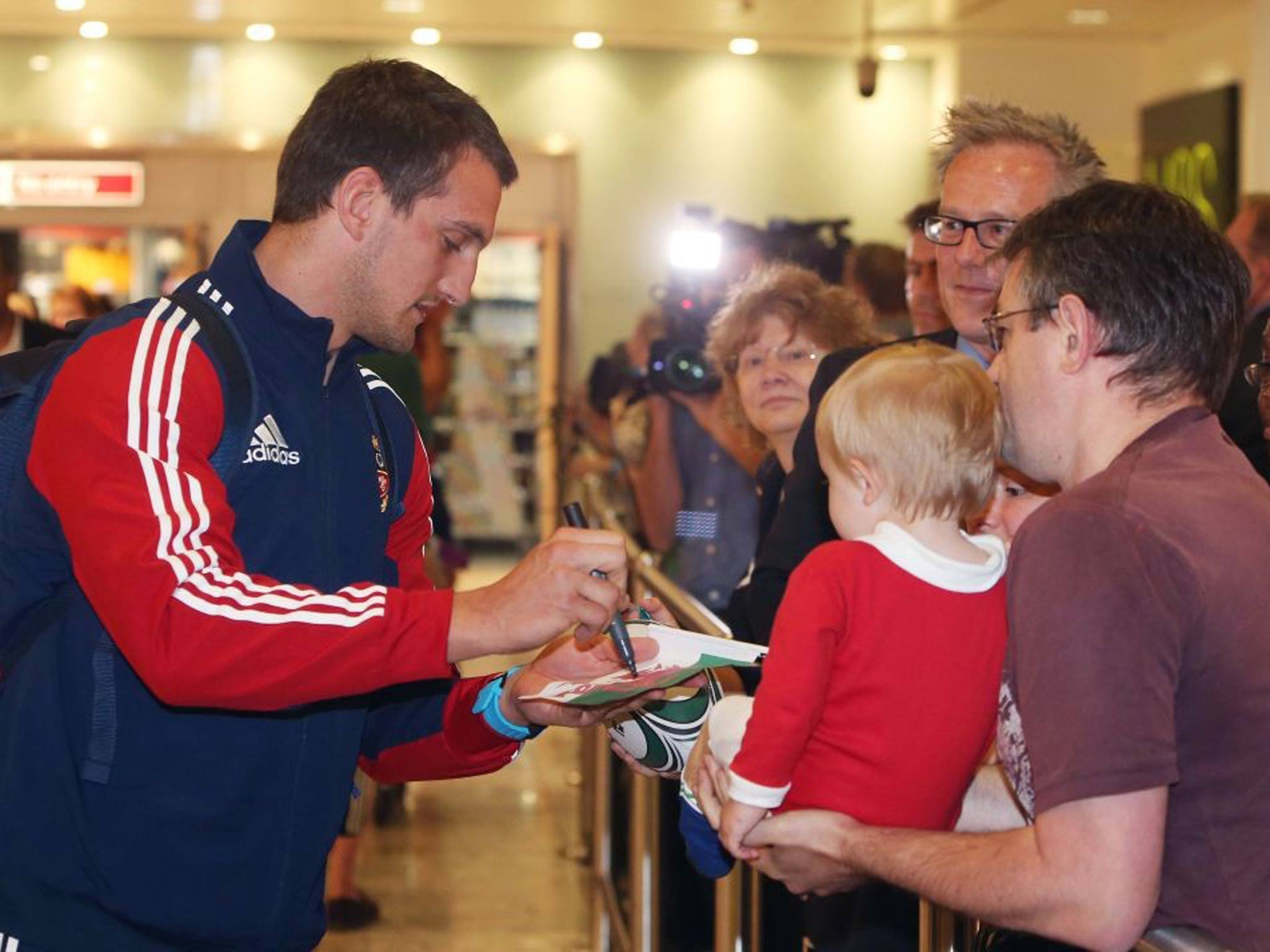 Sam Warburton signs an autograph after arriving at Heathrow Airport