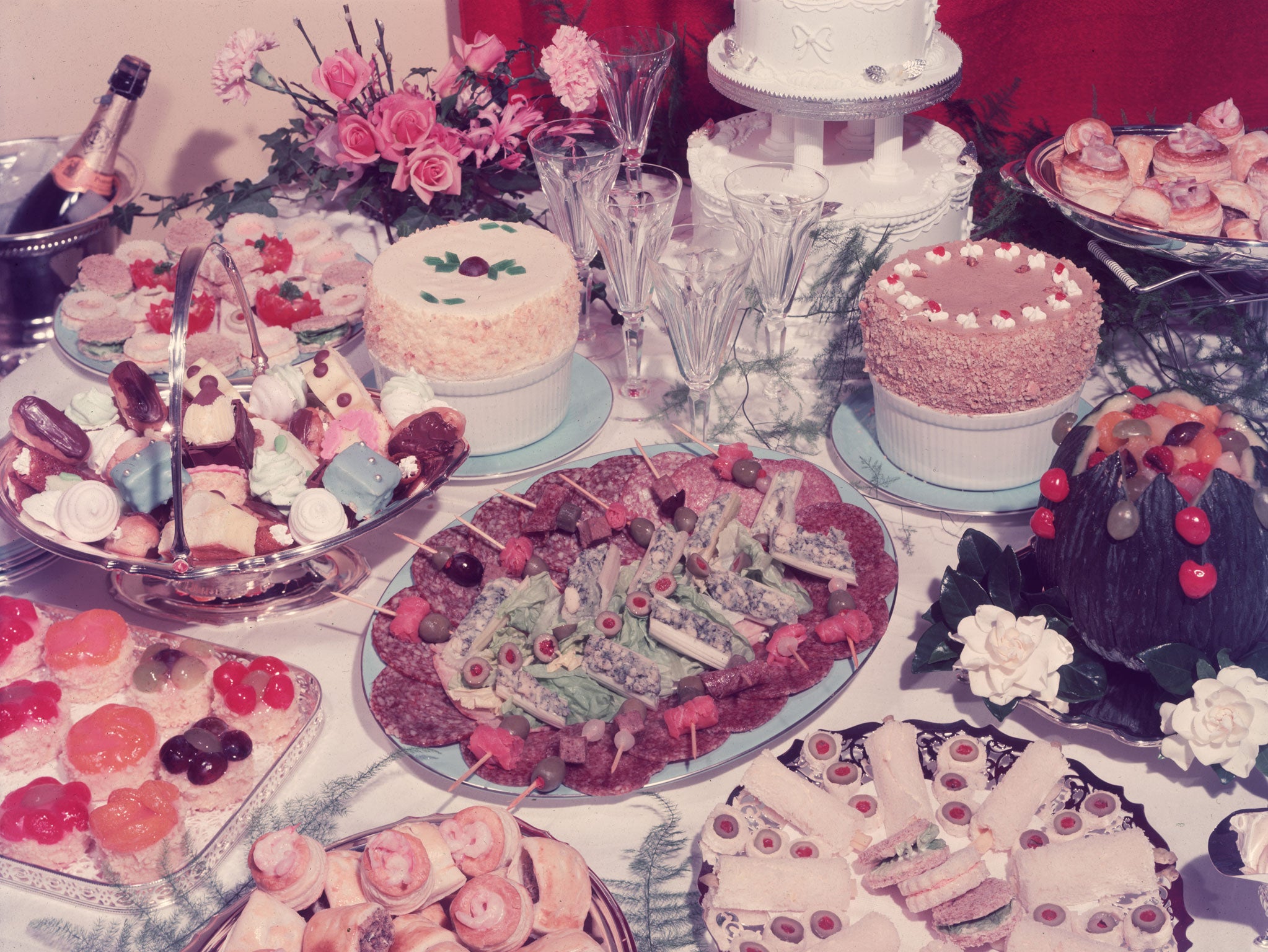 A table at a wedding reception laden with a garish variety of culinary delights, such as cold meats, salads, vol-au-vents and petit-fours.