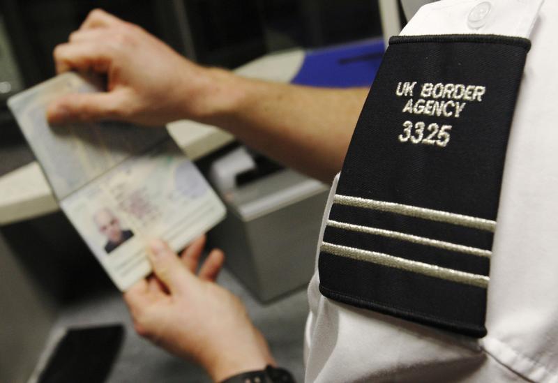 A UK Border Agency worker poses with a passport during a demonstration of the new facial recognition gates at the North Terminal of Gatwick Airport near London, November 23, 2009. The gates can be used by any British or EEA national who holds a biometric